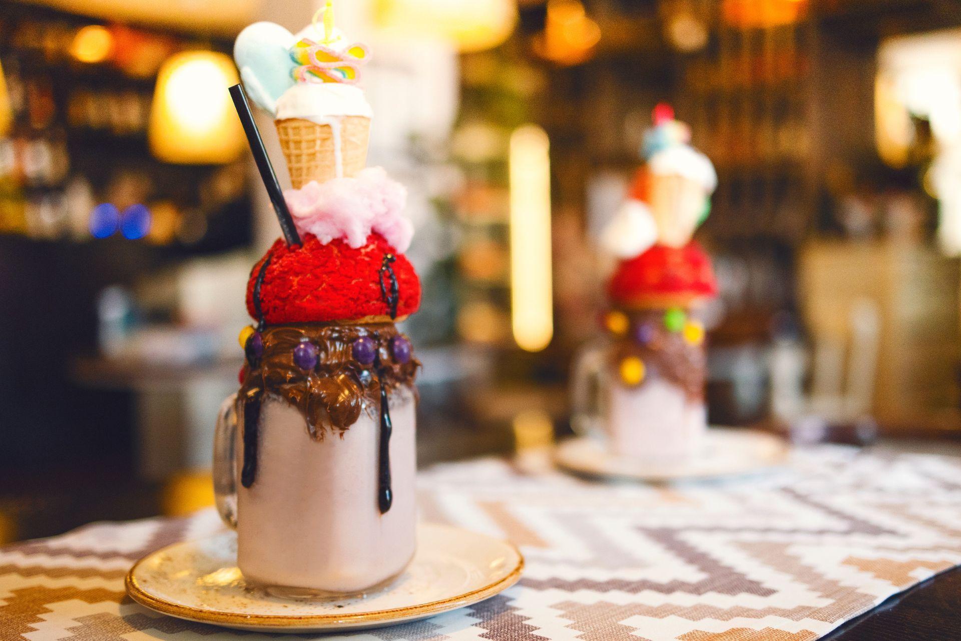 Chocolate milkshake topped with whipped cream and cherries on a bar counter