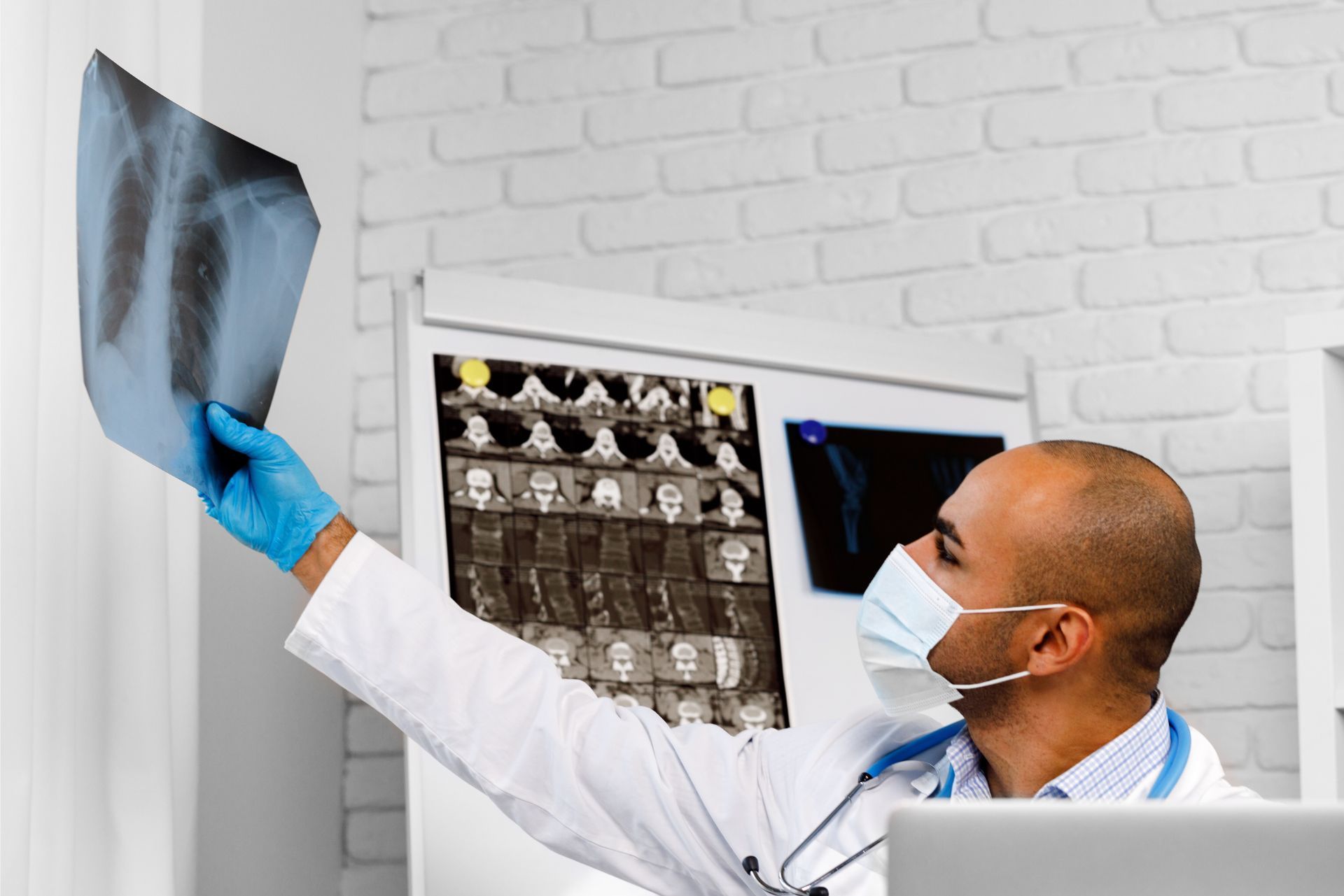 Doctor in mask and blue gloves examining an X-ray in a clinic office
