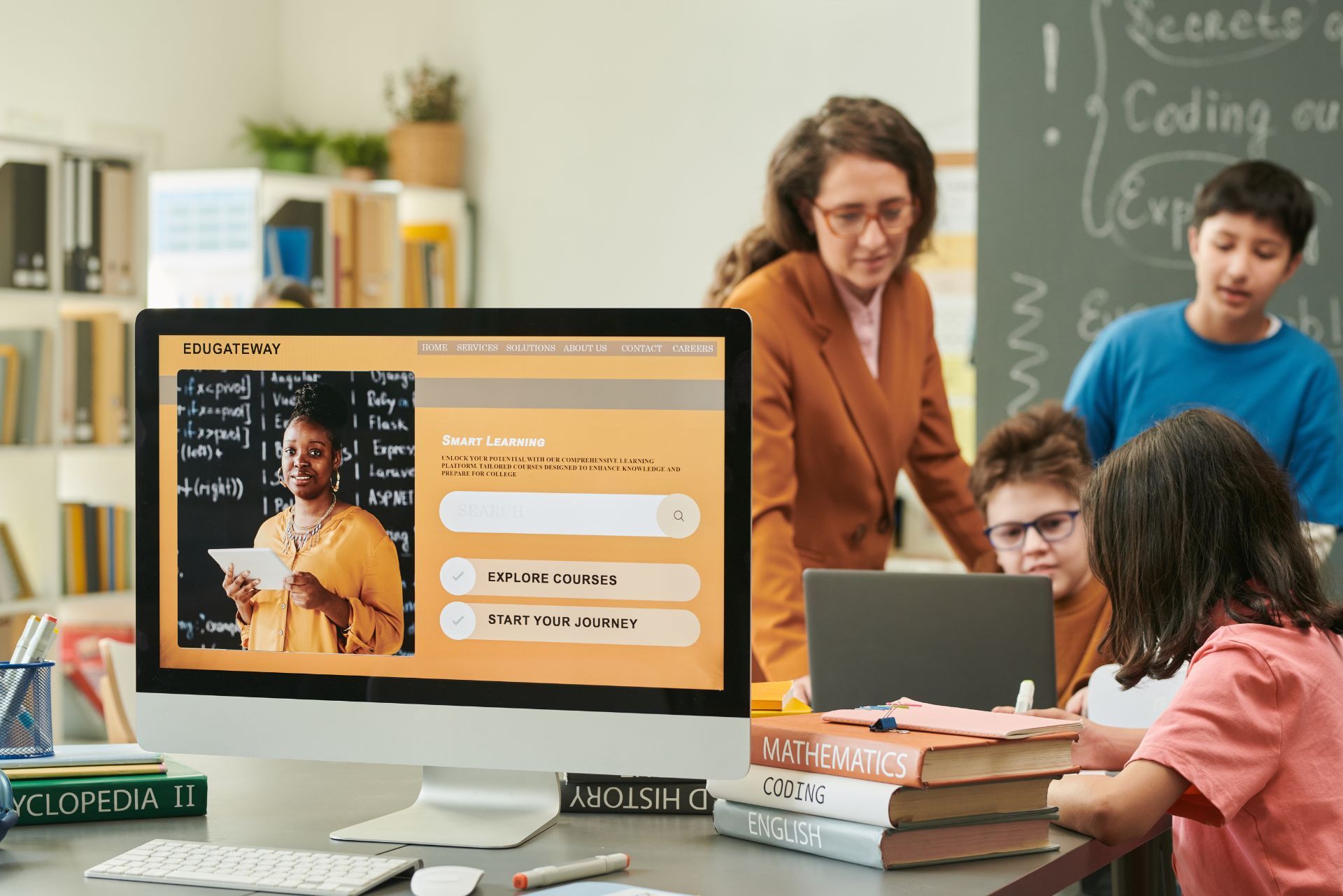 Teacher and students coding in a classroom with a computer showing a programming lesson screen