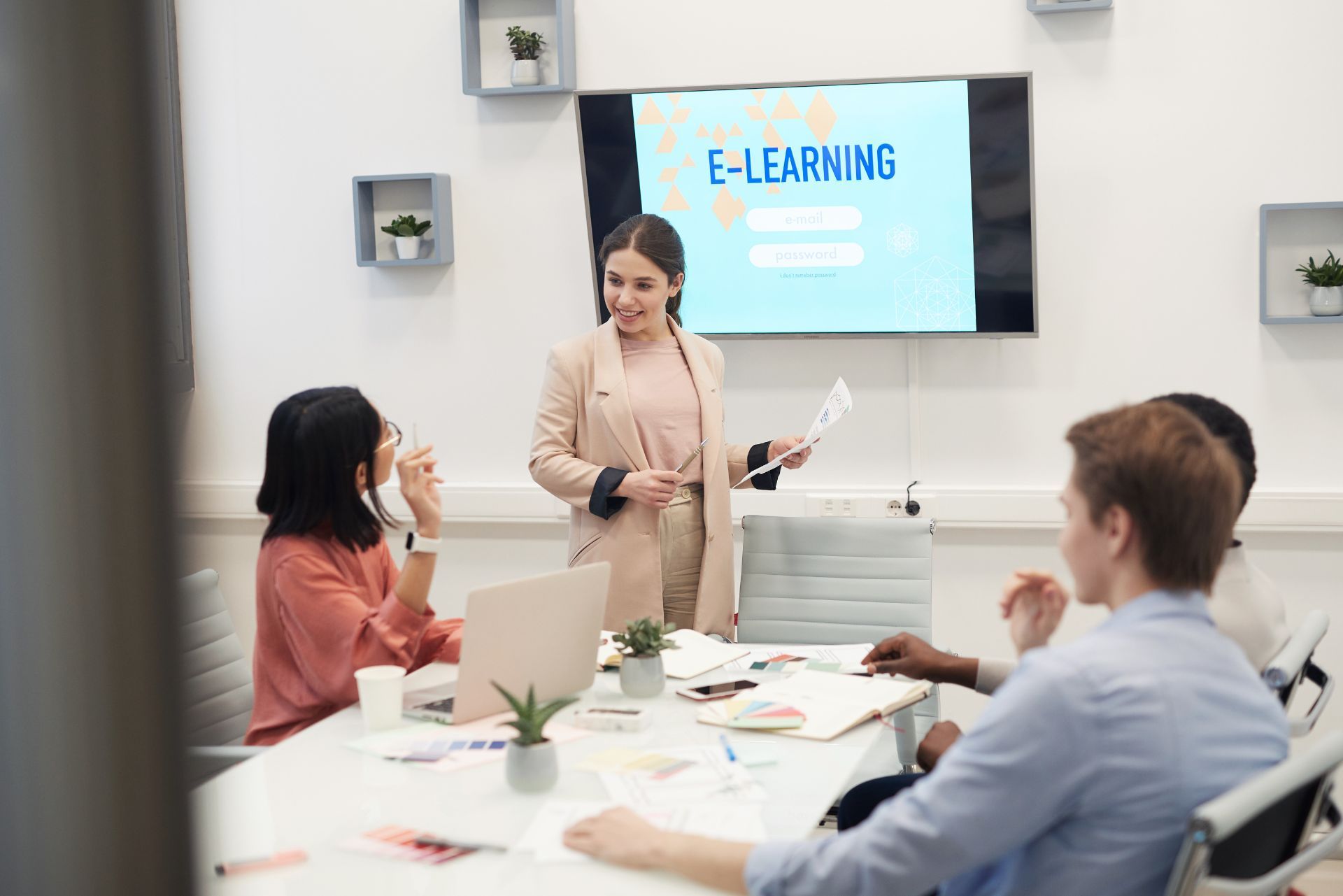 Business meeting with a presenter beside an “E-LEARNING” screen in a bright conference room