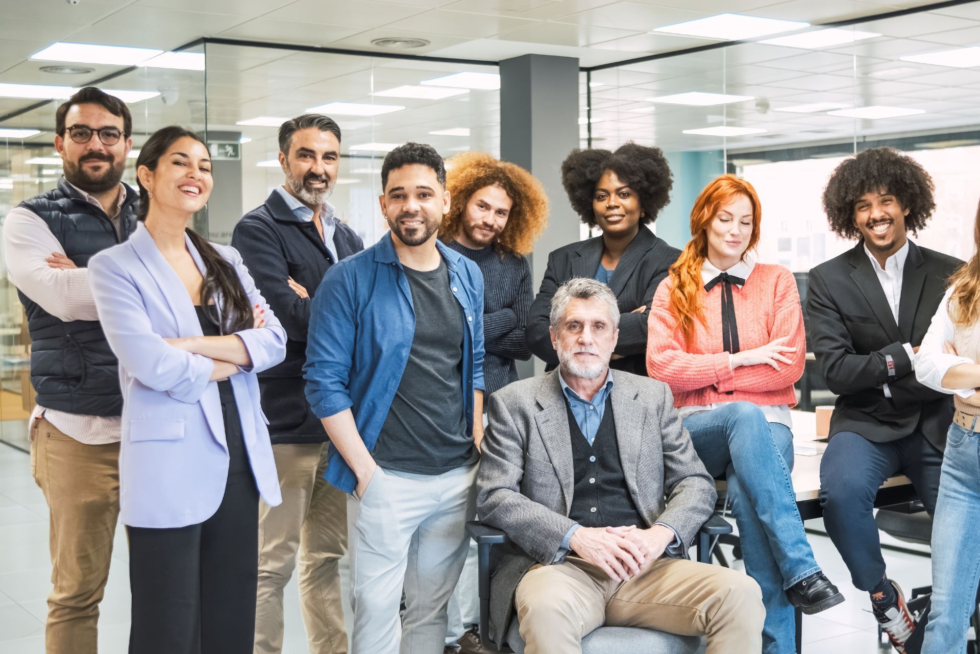 Group of colleagues posing together in a bright office, standing and sitting casually with friendly expressions