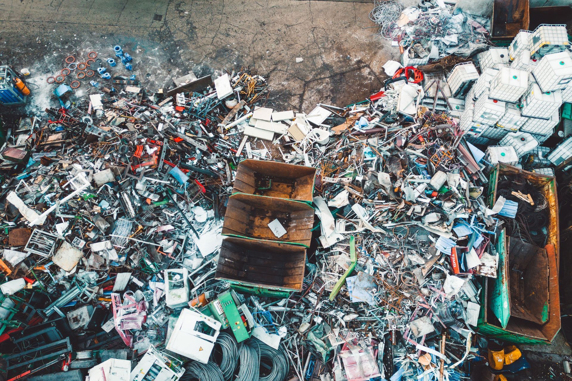 Aerial view of a large landfill with piles of mixed trash and rusted containers.