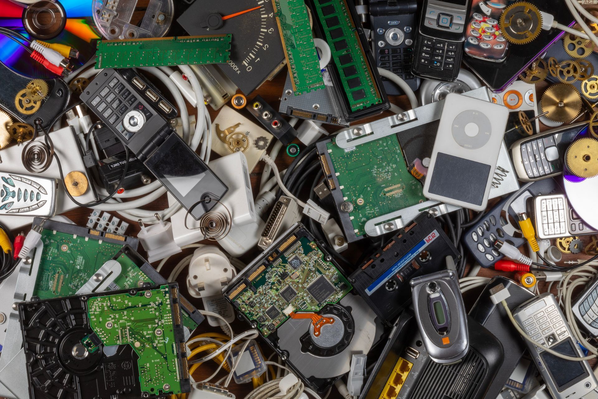 A pile of assorted electronic scrap and circuit boards, with cables, chips, and broken devices cluttered together