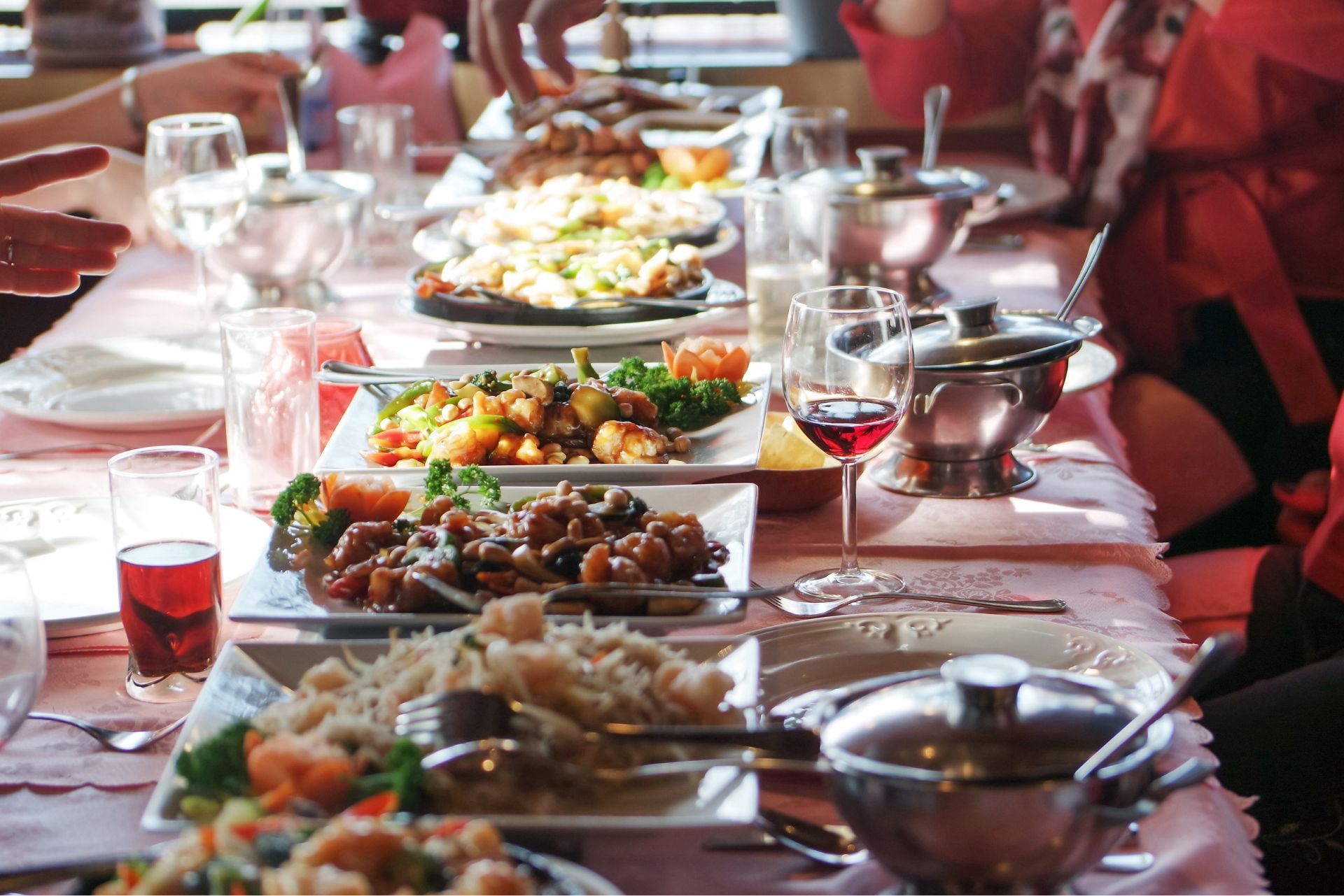 Long dining table set with platters of food and glasses in a warmly lit restaurant