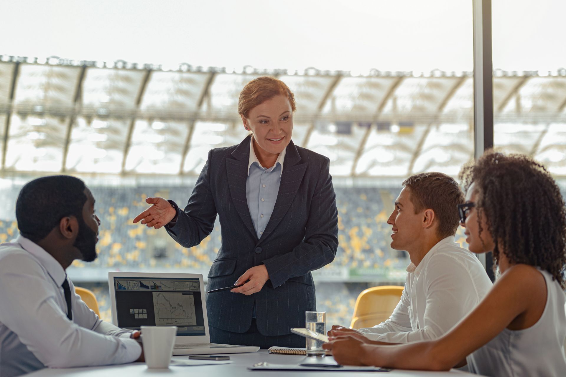 Business meeting with a presenter speaking to three colleagues around a conference table in a bright office