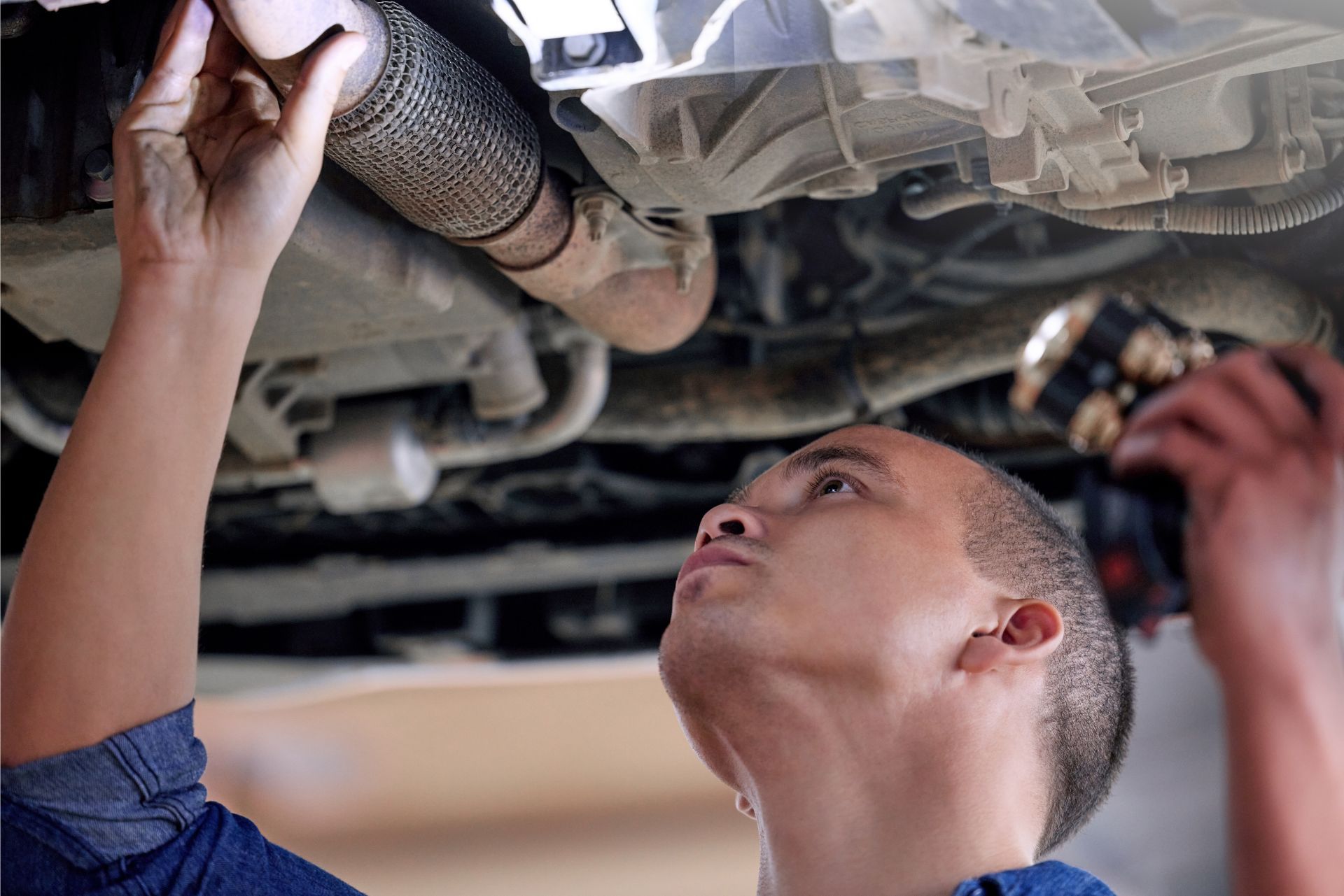 Mechanic inspecting a car’s underside on a lift in a garage