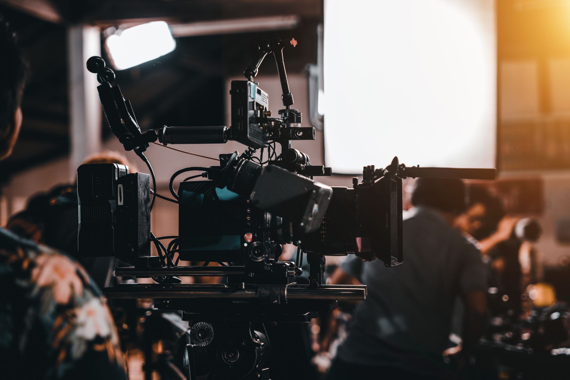 Film camera rig on a set with bright studio light and crew in the background