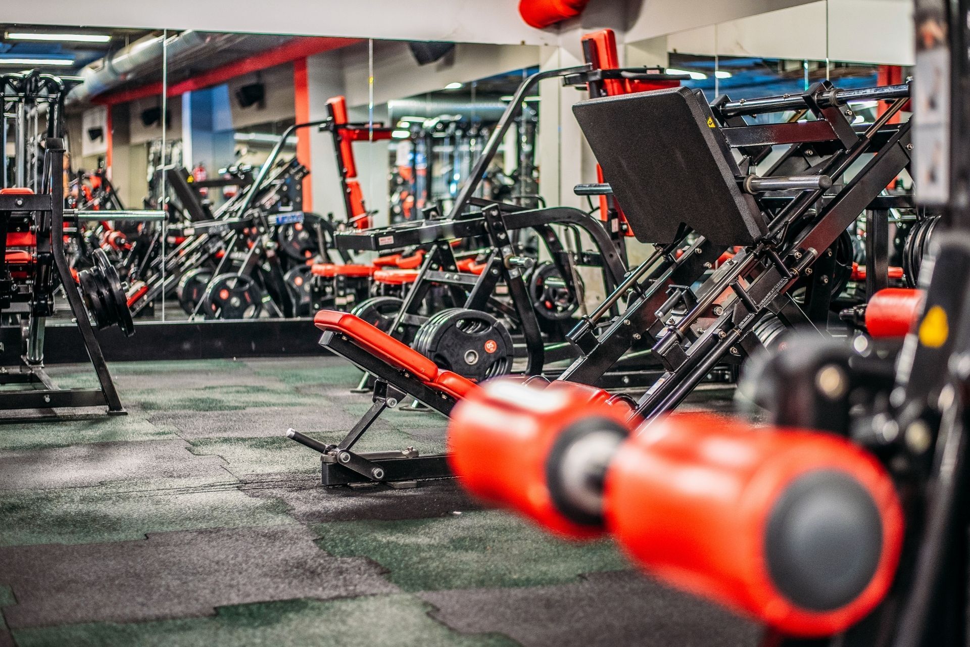 Gym interior with rows of red-and-black weight machines and workout benches