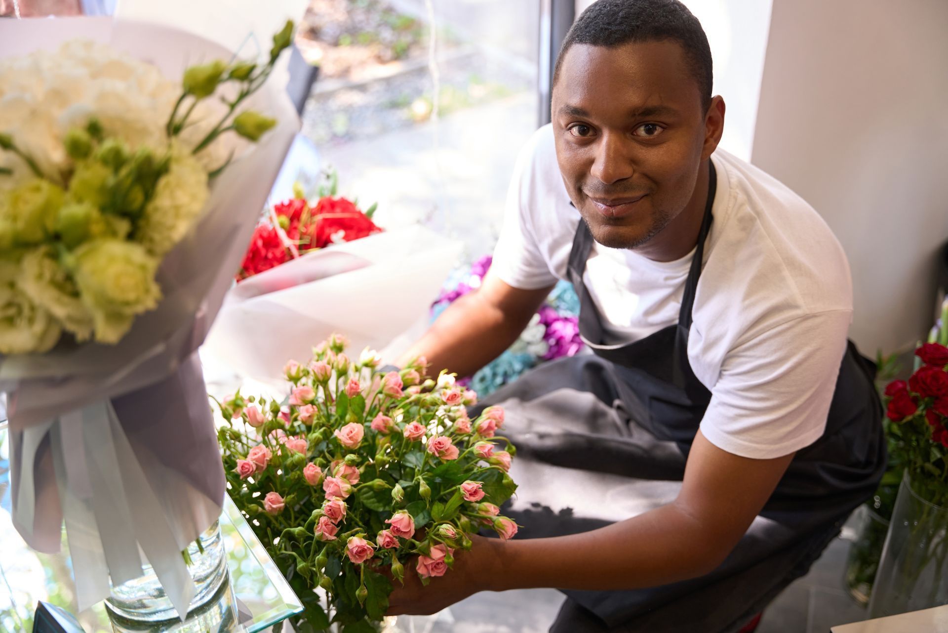 Florist arranging a bouquet of pink flowers on a table