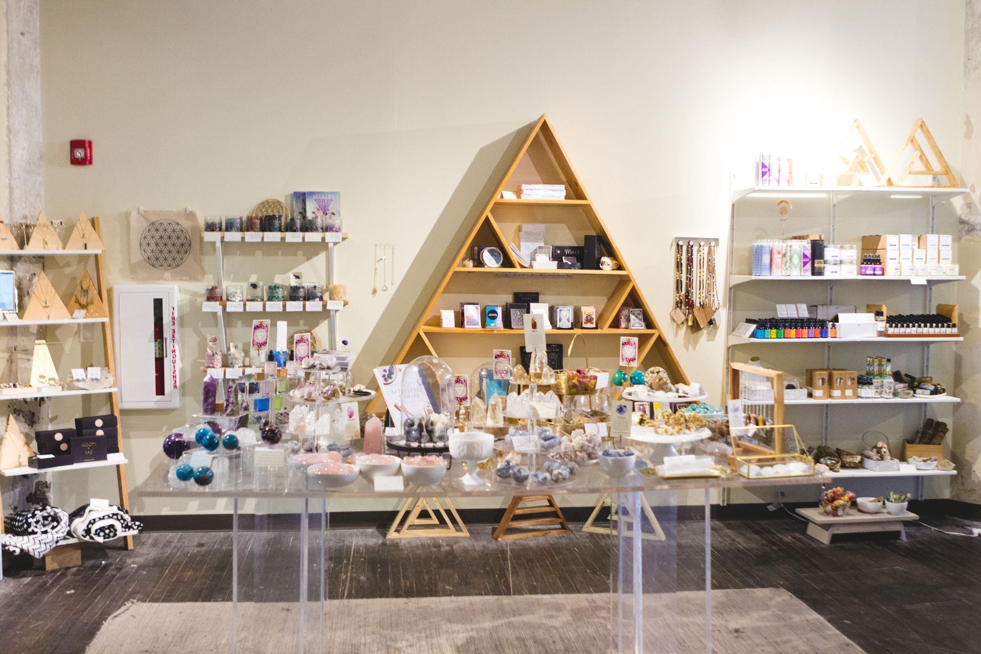Display of handmade goods on shelves and tables in a bright boutique with wooden triangular shelves