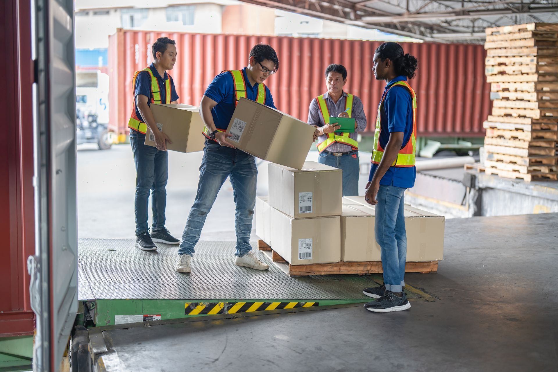Workers in safety vests loading cardboard boxes in a warehouse loading dock