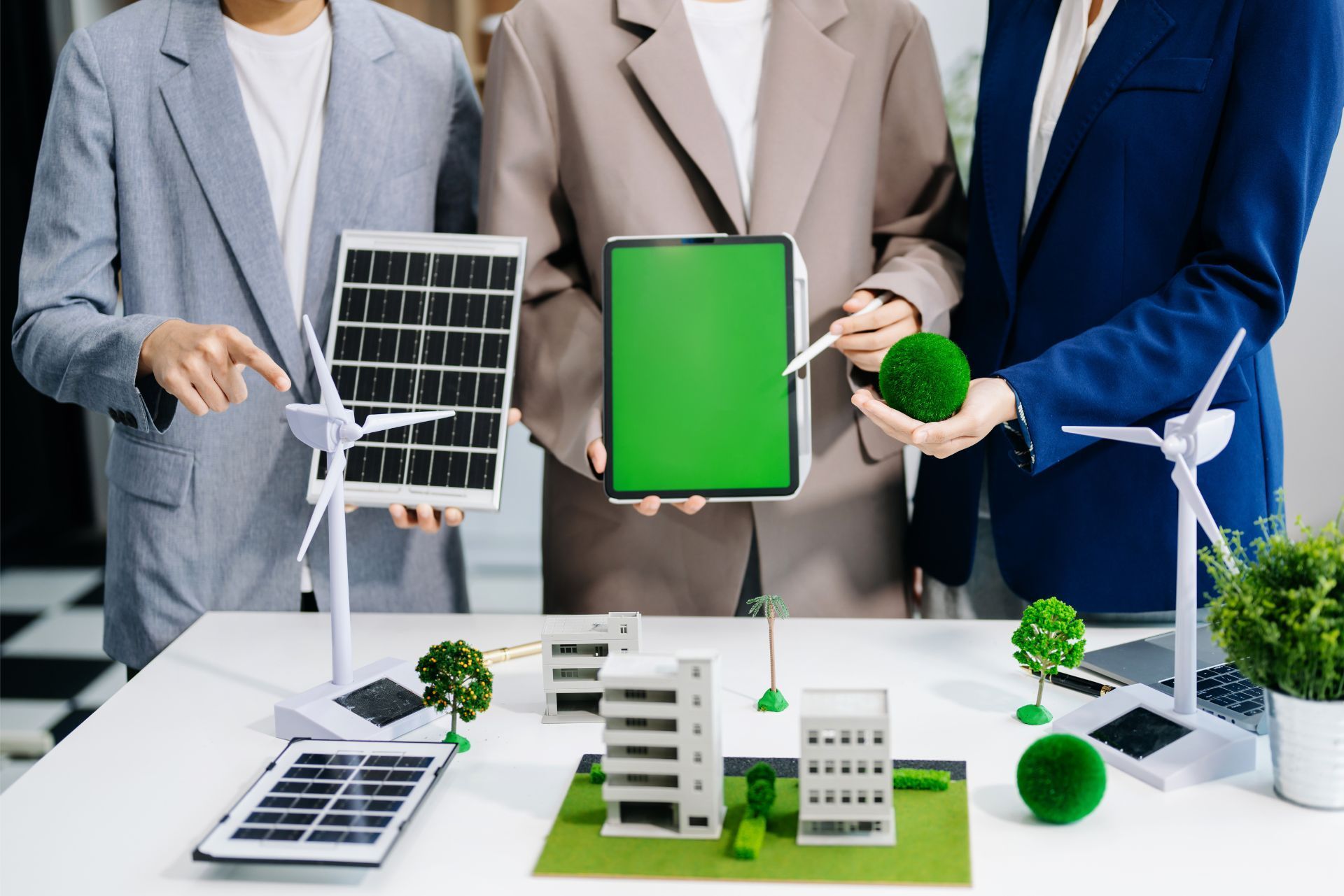Three people in professional attire hold a solar panel, a tablet with a green screen, and a green sphere above a model city.