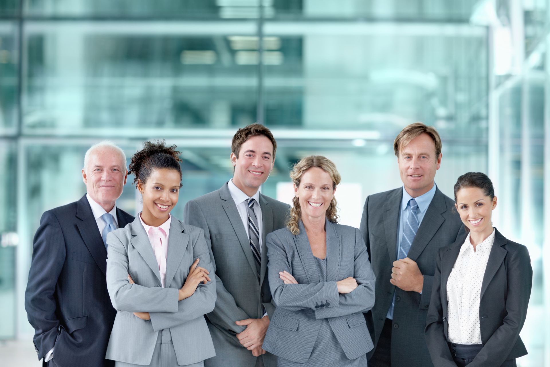 Six business professionals in gray suits standing together in a bright office lobby
