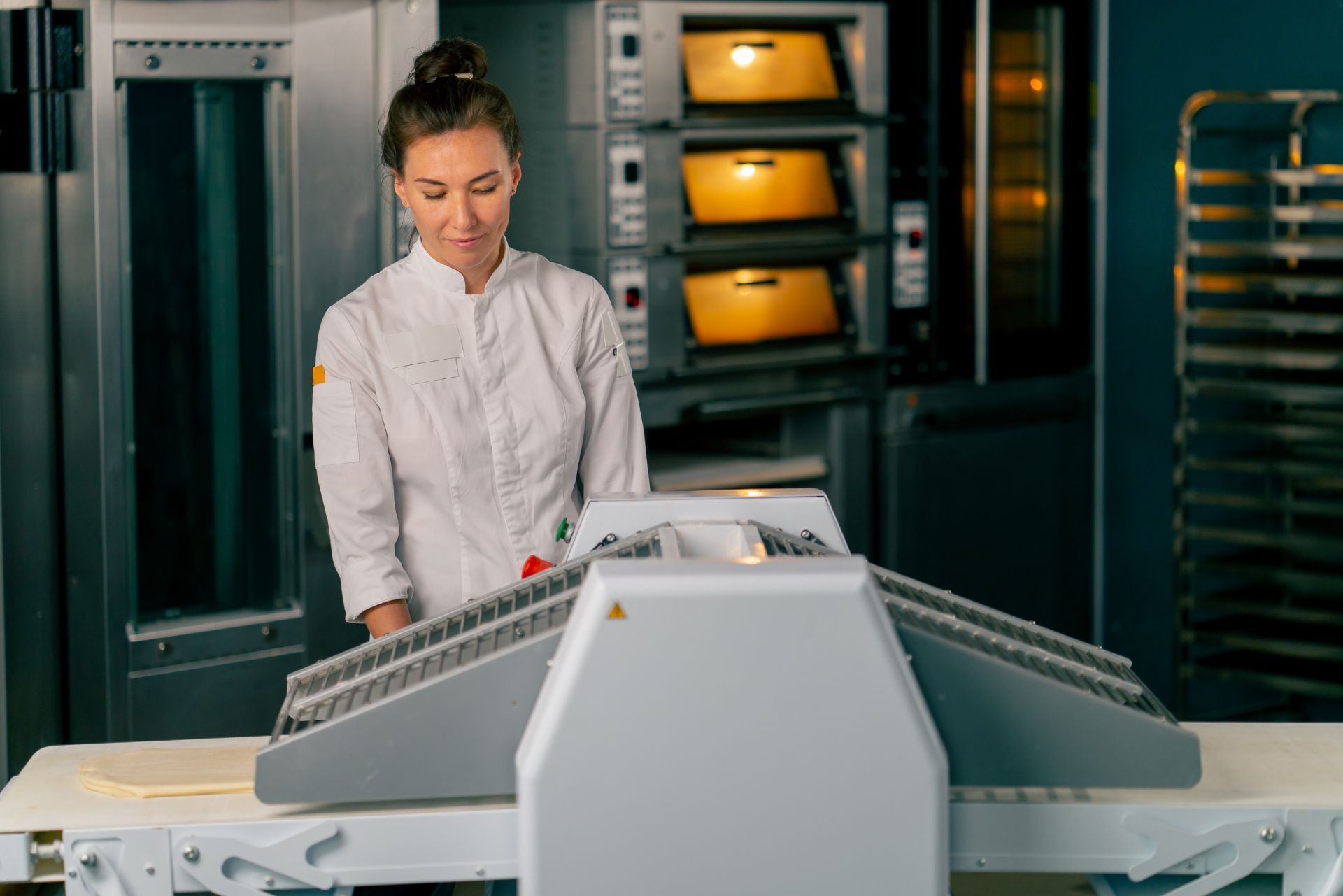 Woman operating industrial food-processing machine in a commercial kitchen