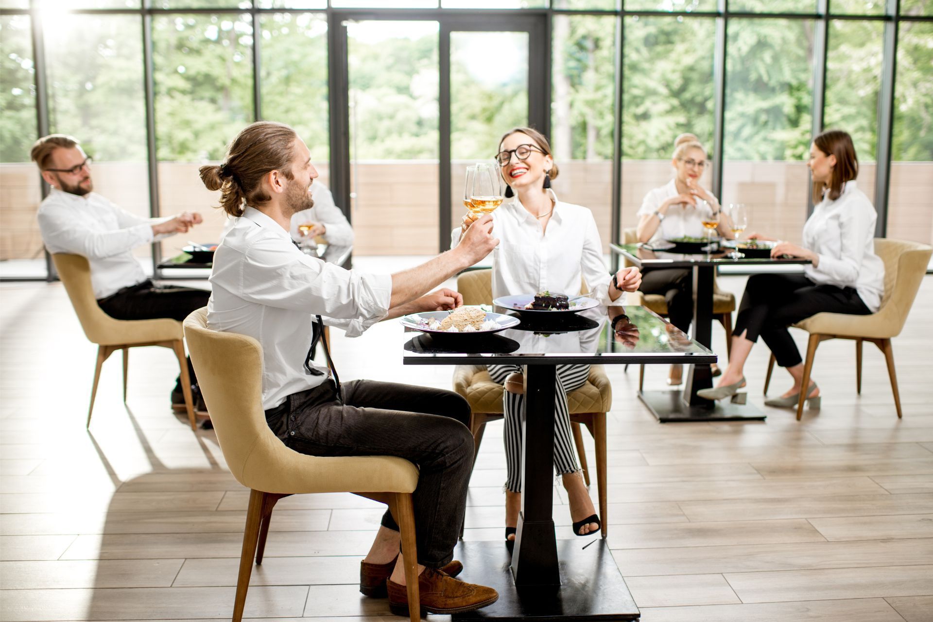 People in a bright office meeting, talking around a table with laptops and coffee cups