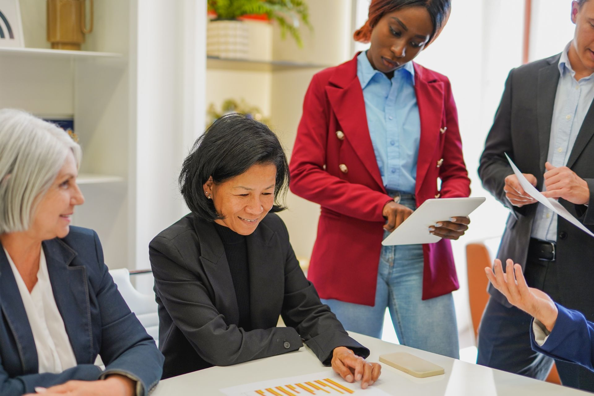 Colleagues discussing documents at a table in a bright office meeting room