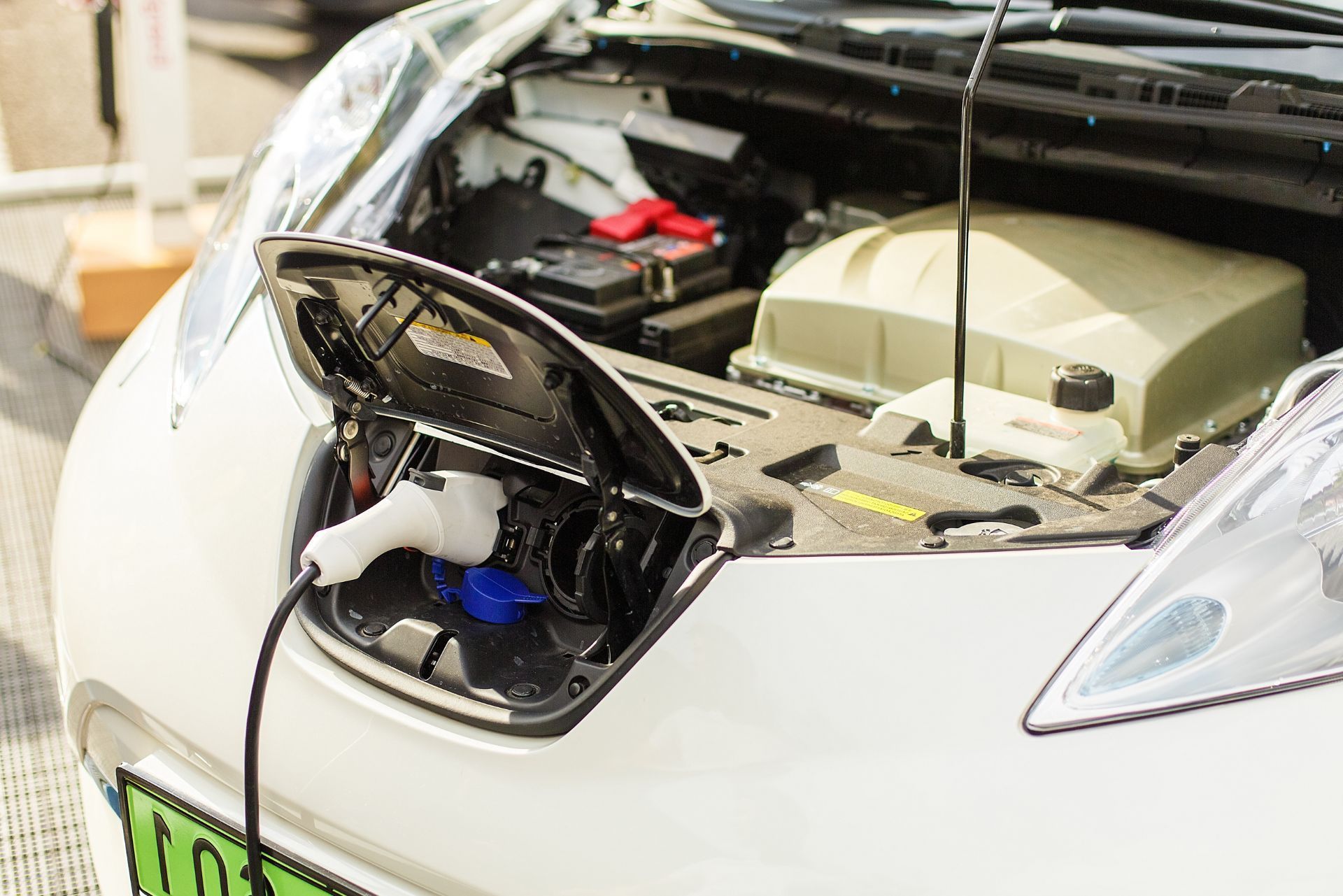 Car with open front trunk, showing exposed engine components and wiring under the hood.