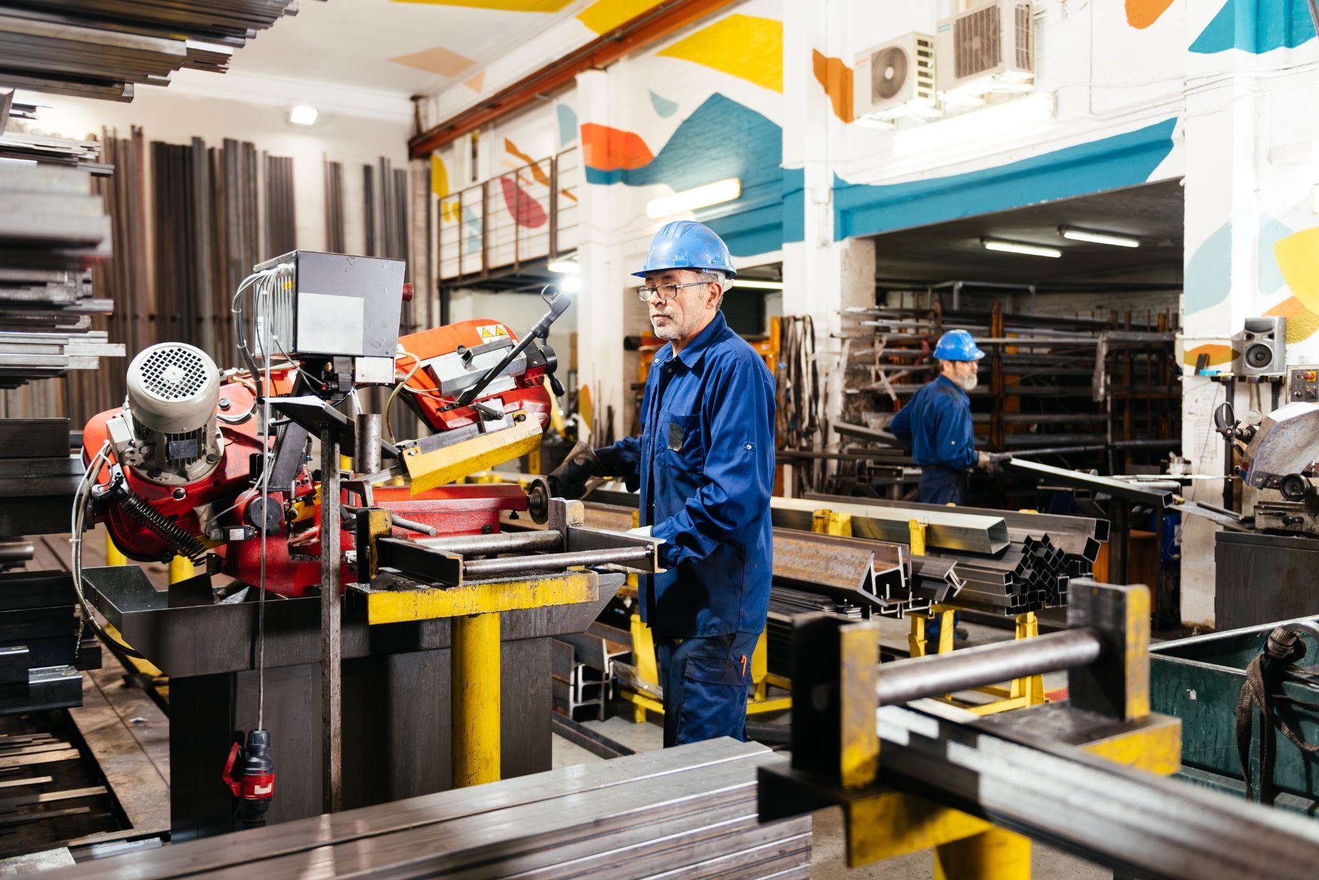 Workers operating machinery in a bright factory workshop with metal equipment and tools