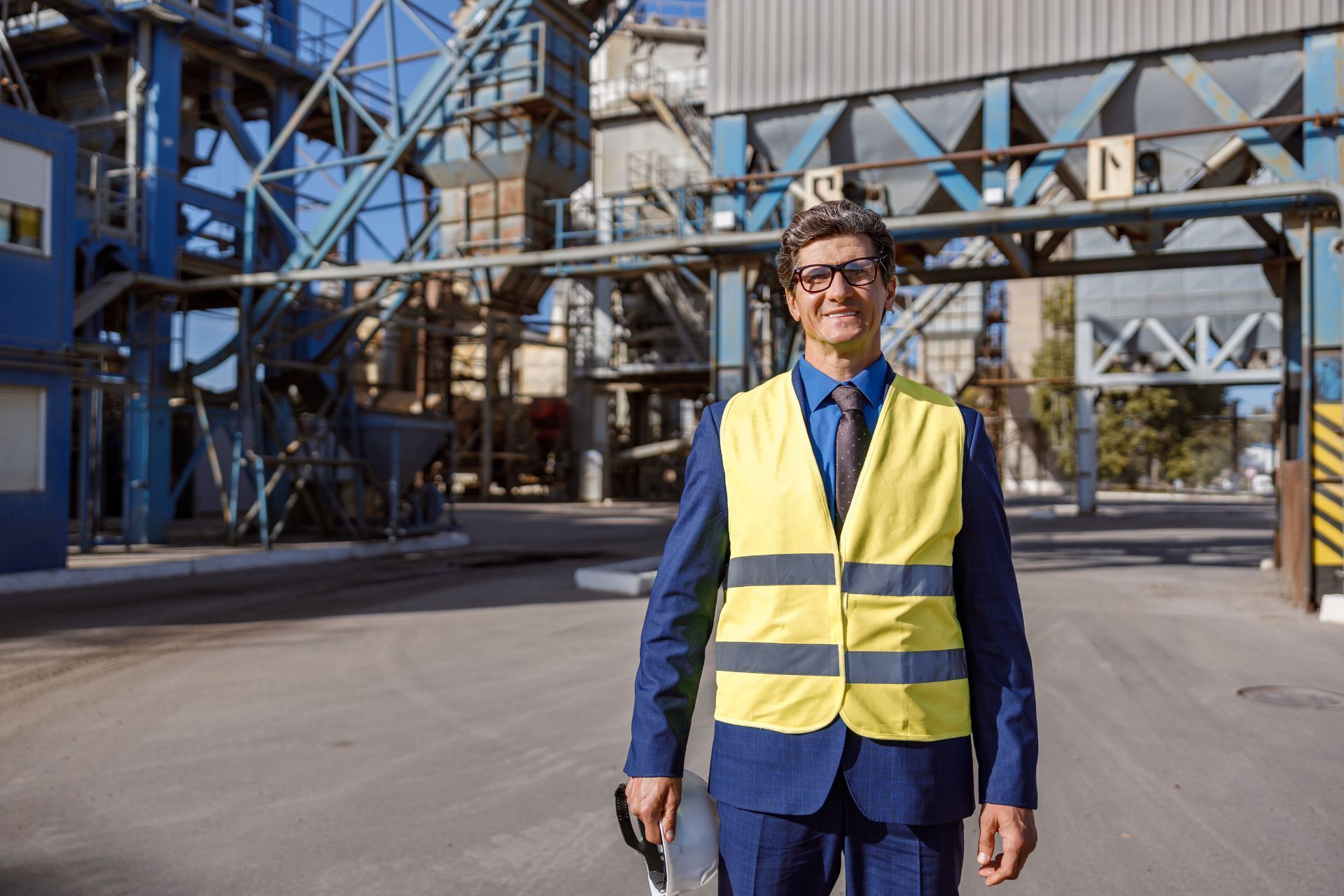 Person in a yellow safety vest standing in an industrial facility courtyard.