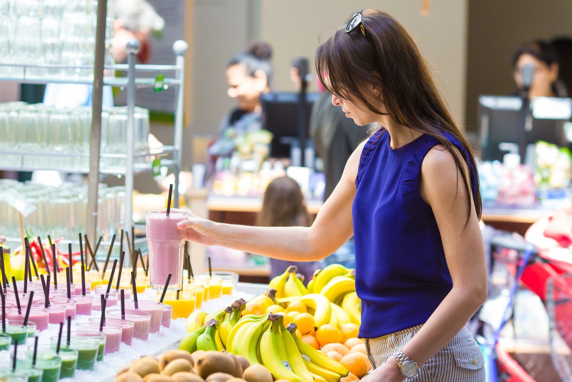 Woman choosing fruit and smoothies at a colorful market stall