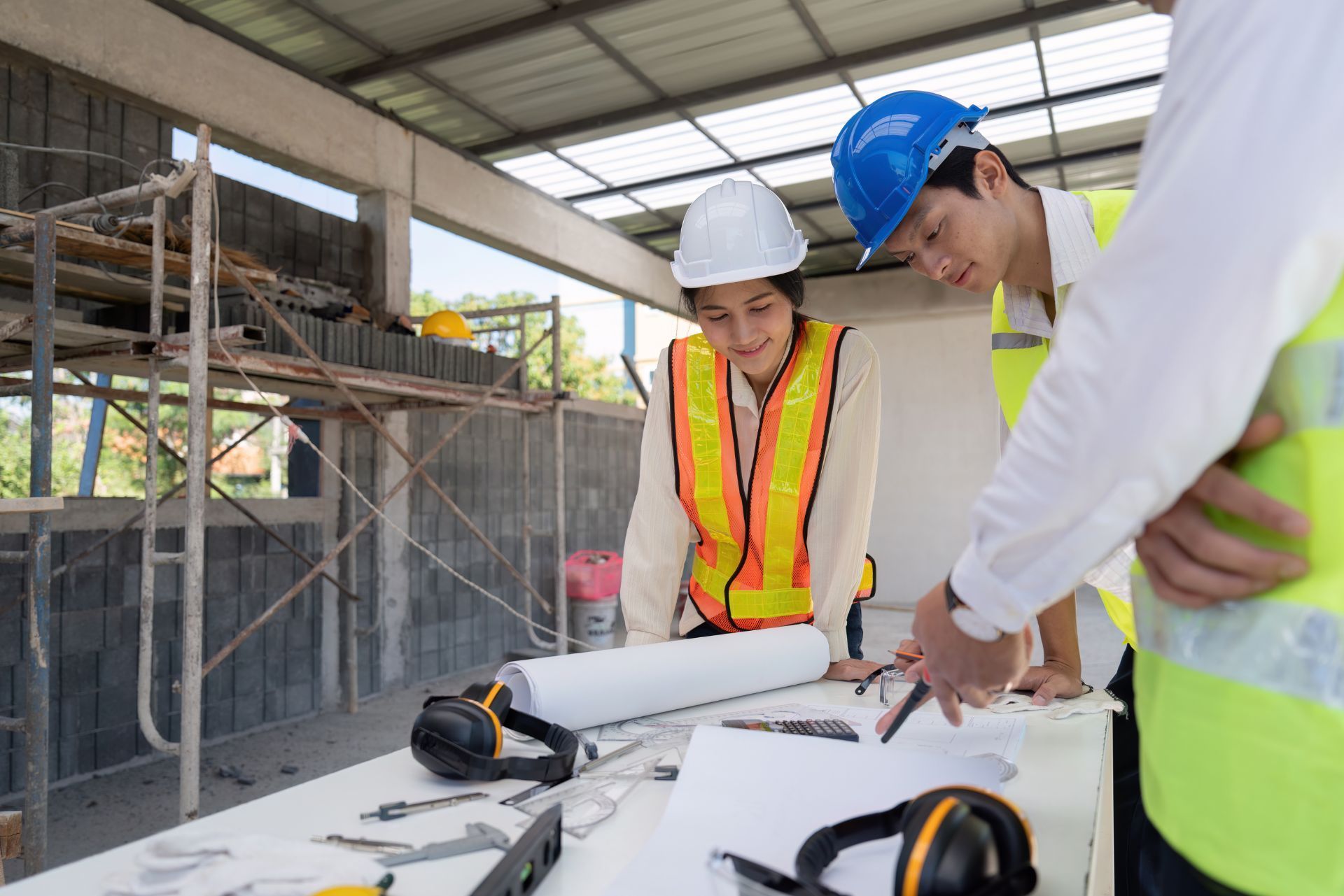 Construction workers in hard hats reviewing blueprints at a building site