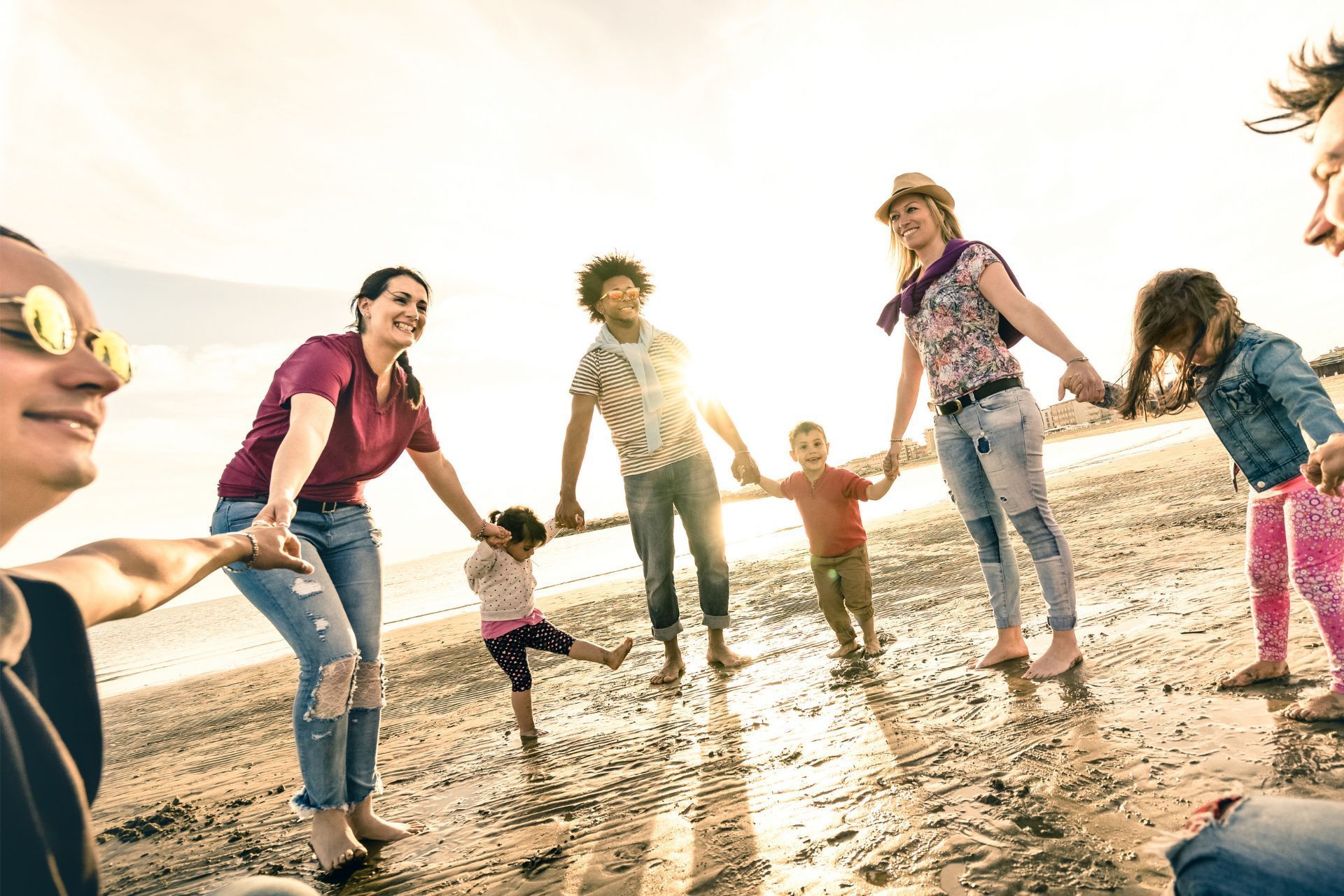 Friends holding hands and jumping on a sunny beach at sunset