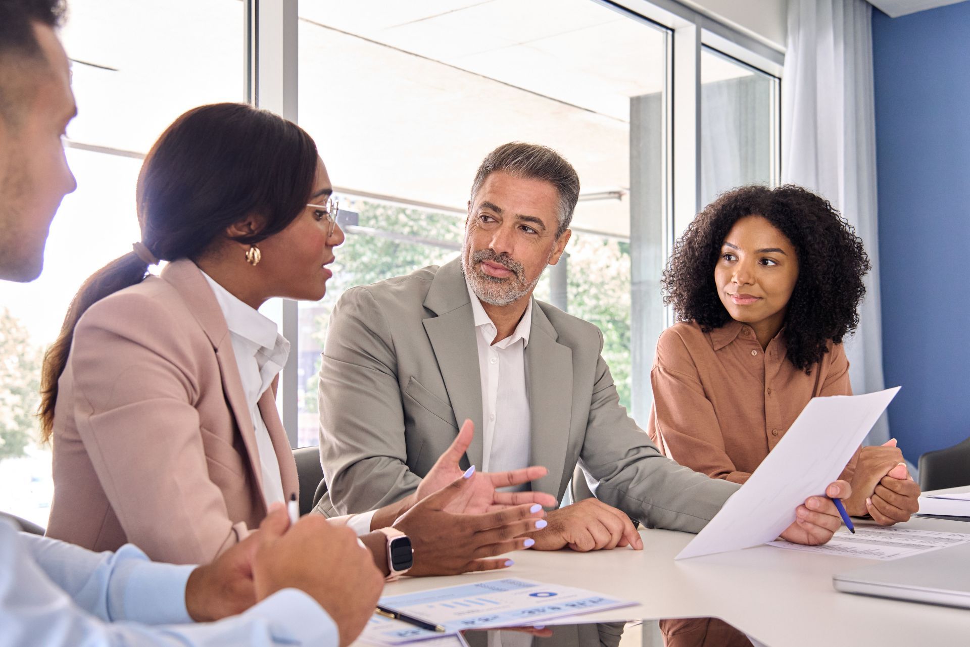 Colleagues discussing papers around a conference table in a bright office