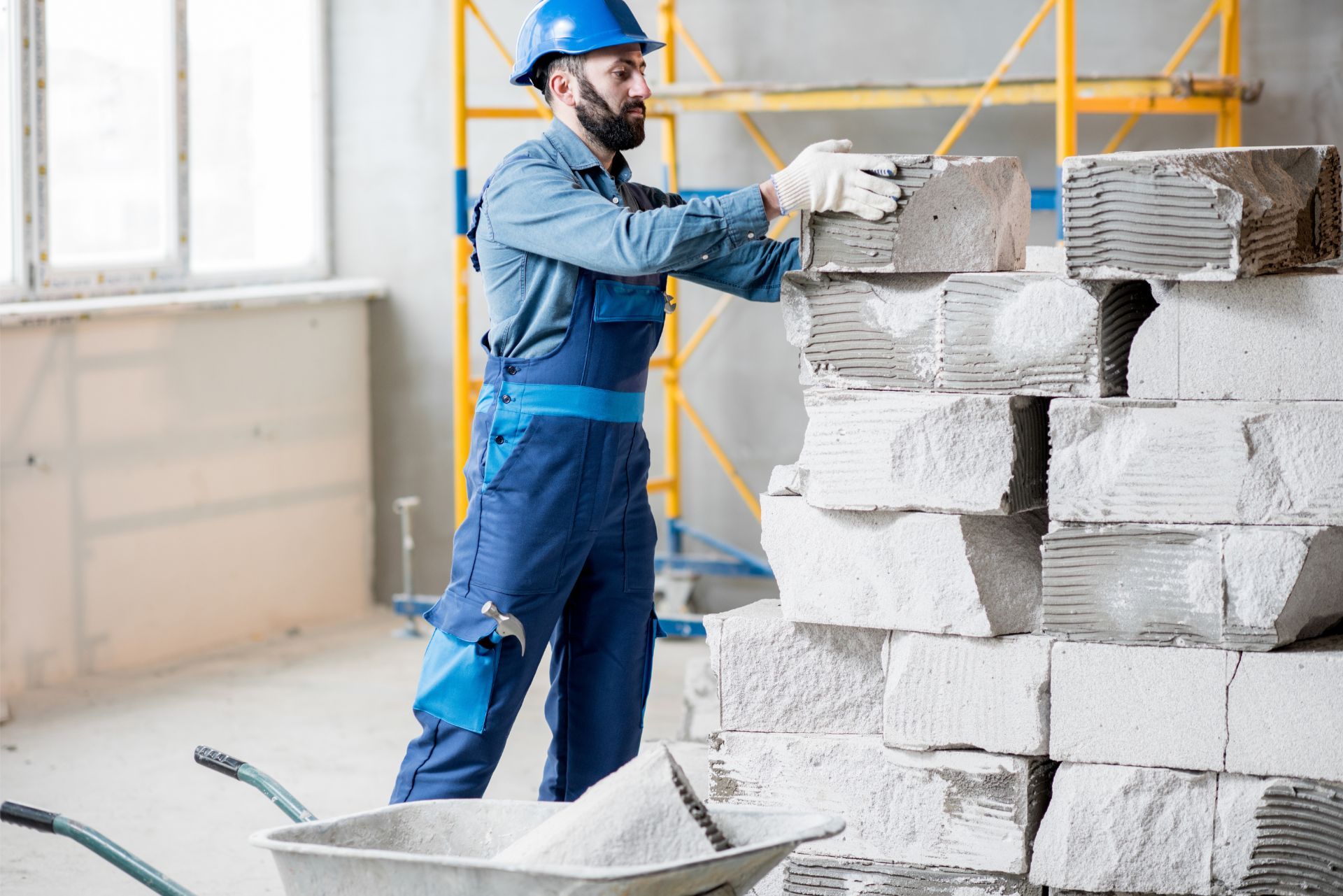 Construction worker stacking concrete blocks in a bright indoor worksite