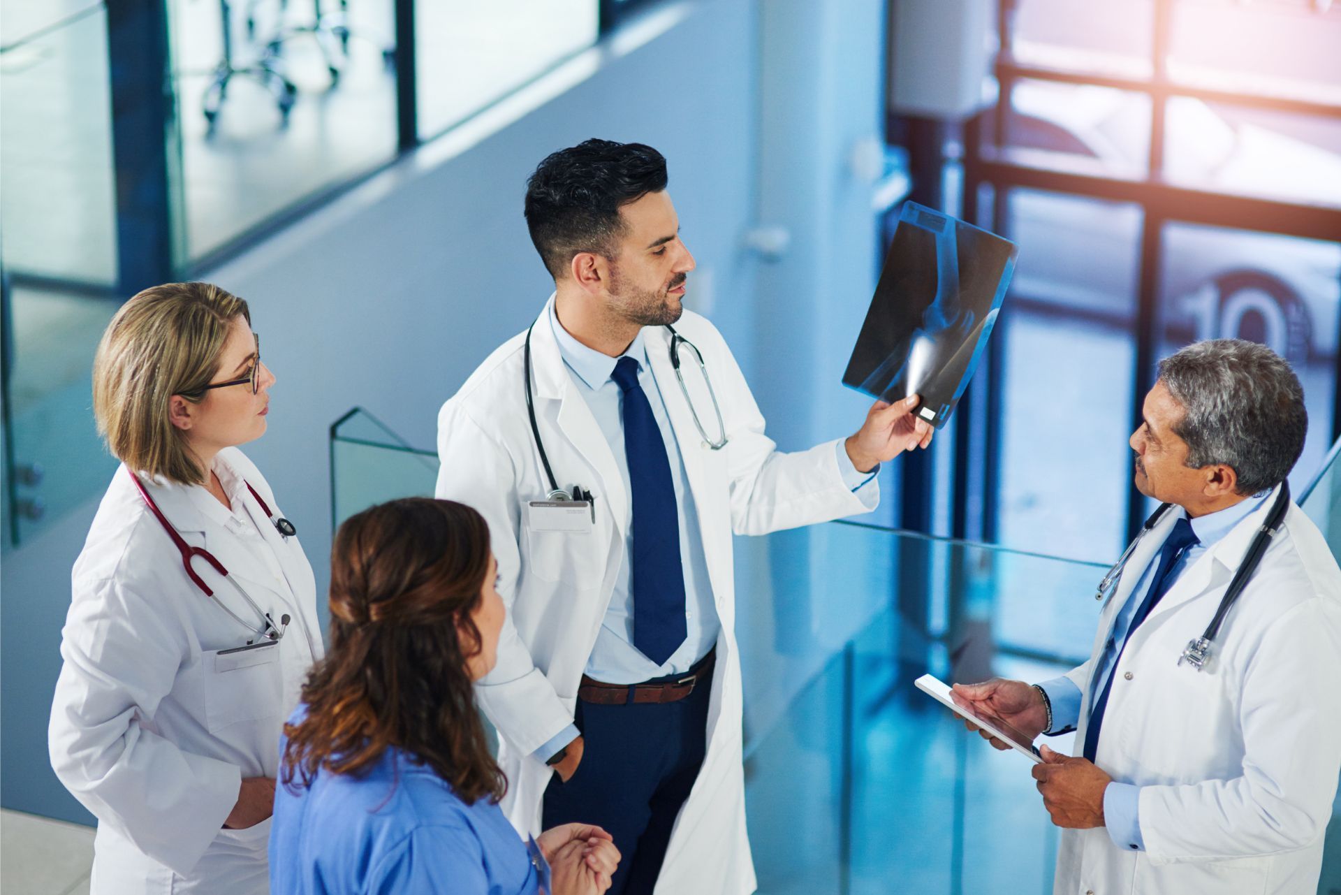 Doctors in a hospital hallway reviewing an X-ray and tablet together