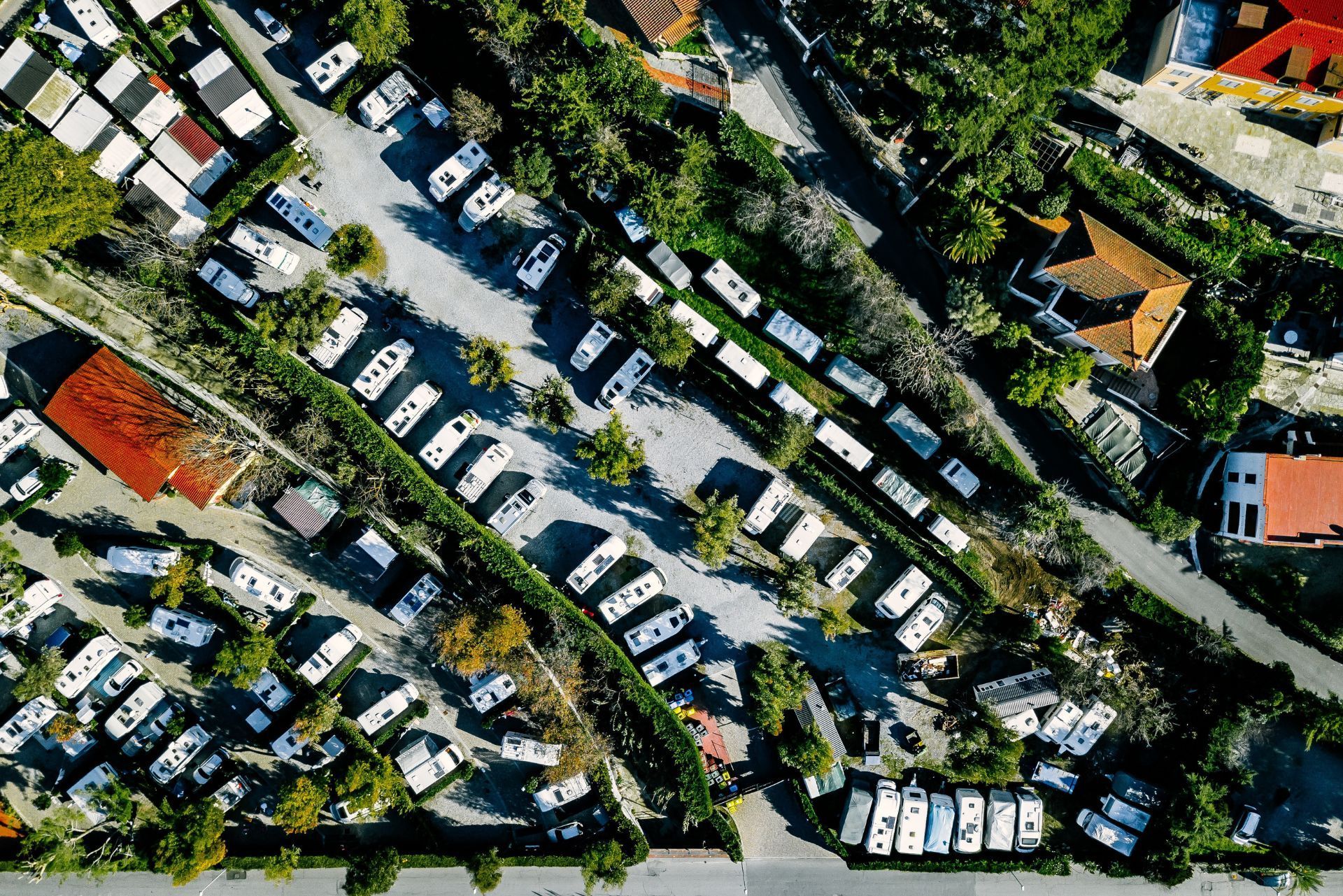 Aerial view of a crowded parking lot with rows of parked cars and surrounding trees and buildings