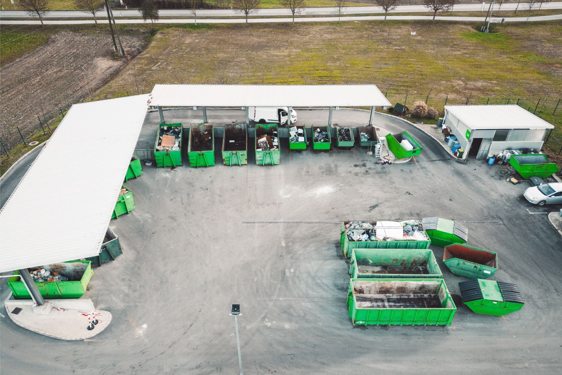 Aerial view of a green-and-white industrial yard with trucks, trailers, and equipment under sheds.