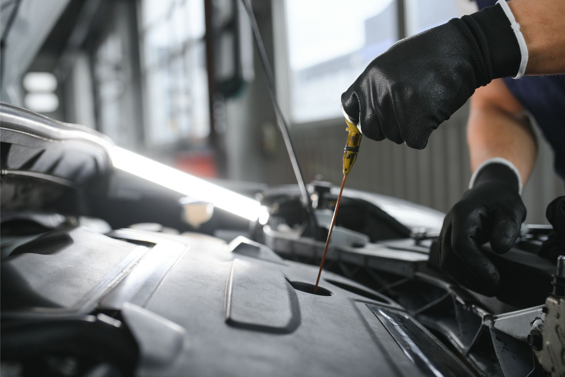 Mechanic adding oil to a car engine in a repair shop