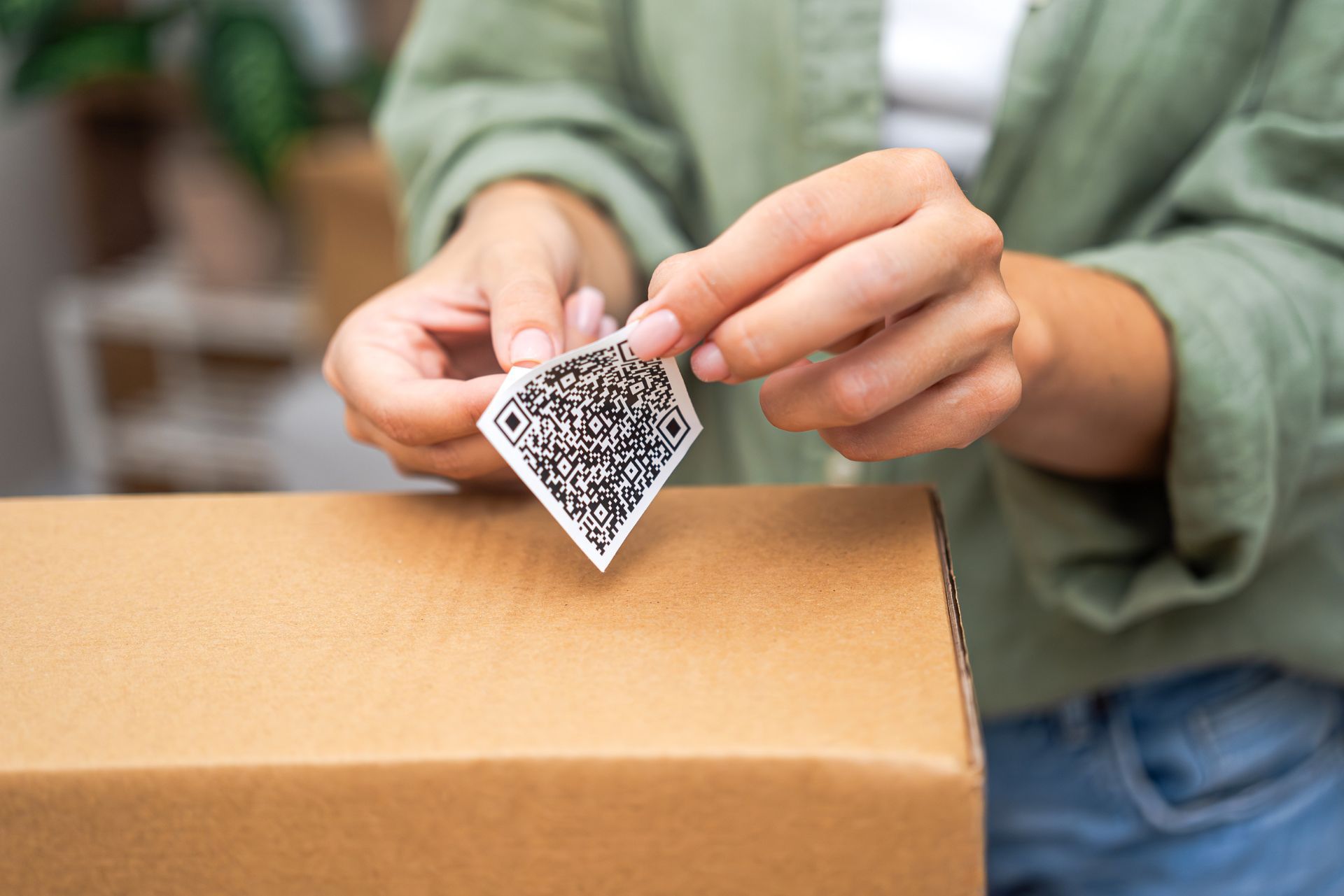 Hands placing a small patterned tag on a cardboard box