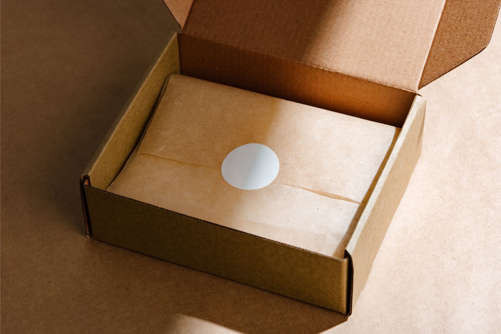 Open cardboard box with a white circular sticker on the inside bottom