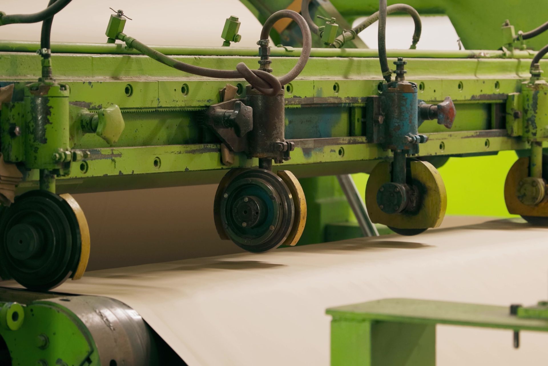 Green textile machine processing white fabric in a factory
