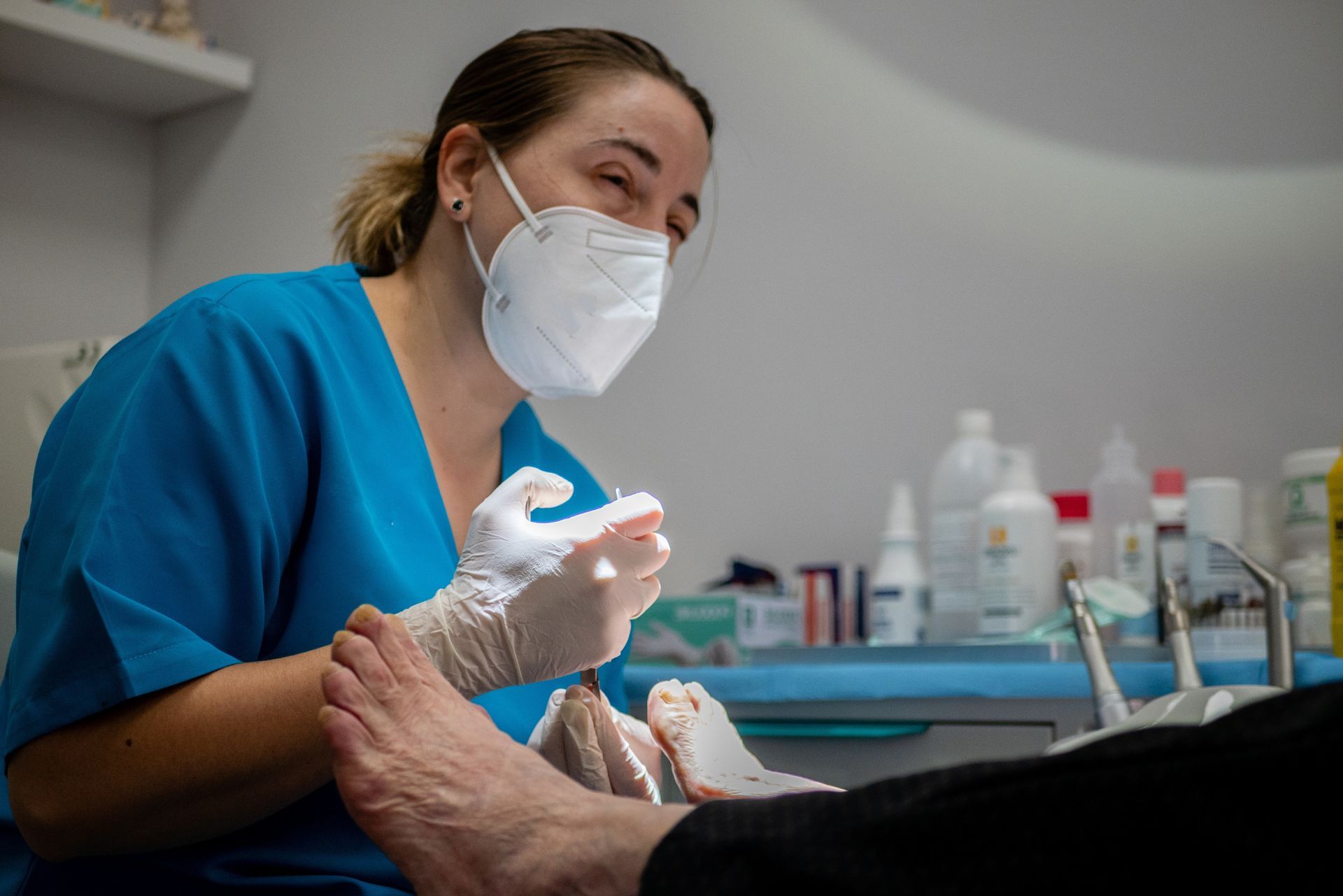 Dentist in blue scrubs and mask examining a patient’s mouth in a dental clinic