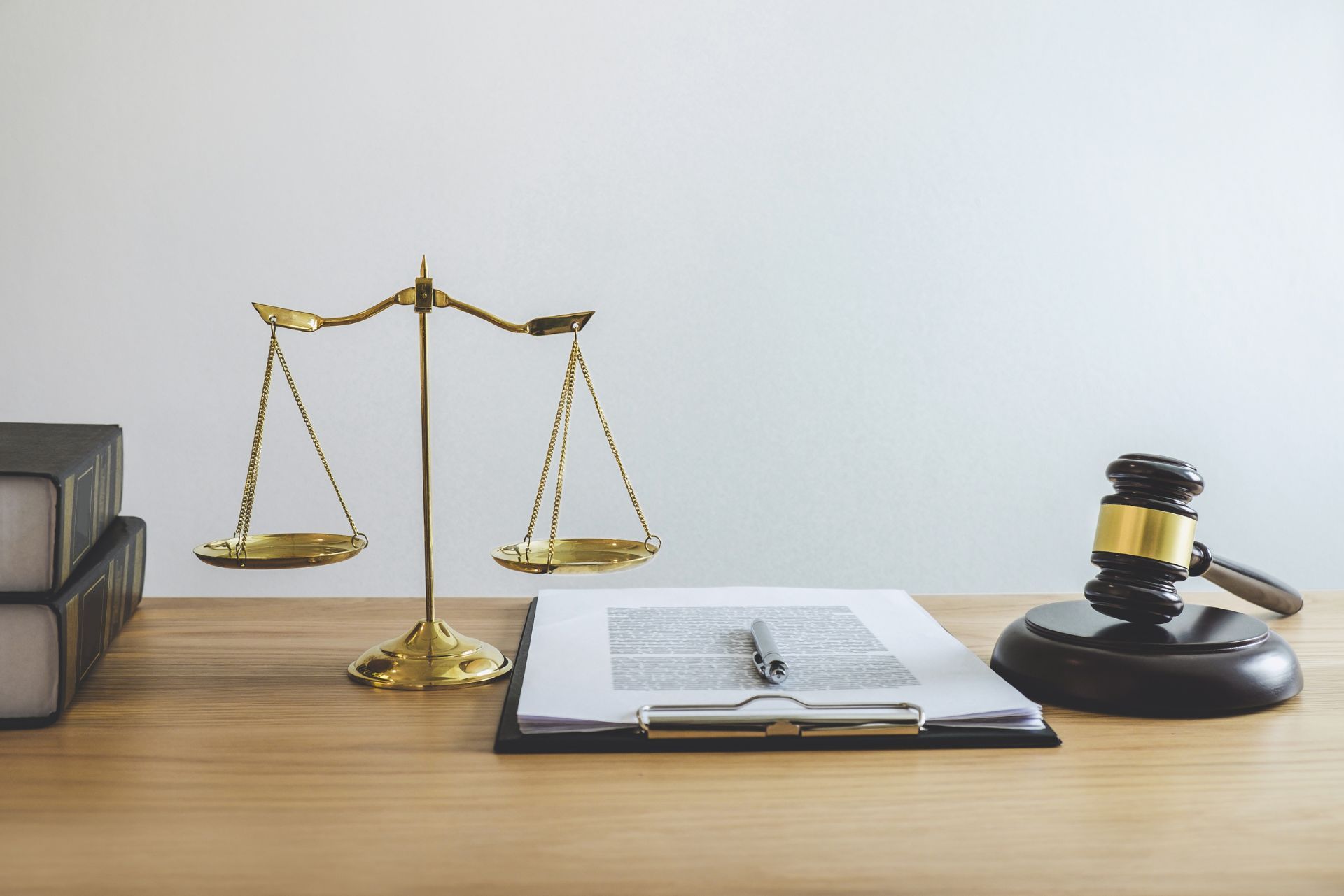 Law scales, open notebook, and gavel on a wooden desk