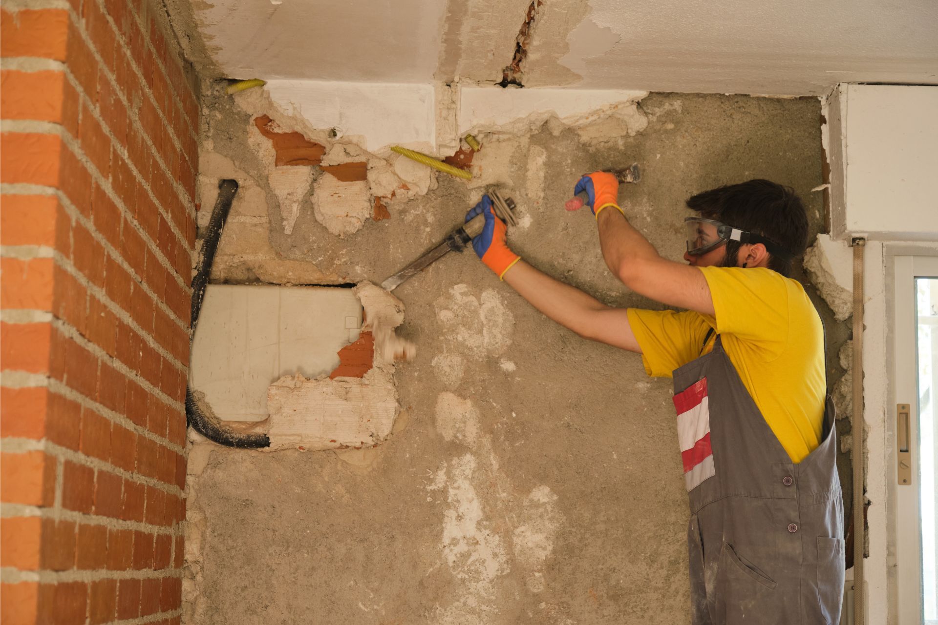 Worker drilling a damaged wall corner during interior renovation