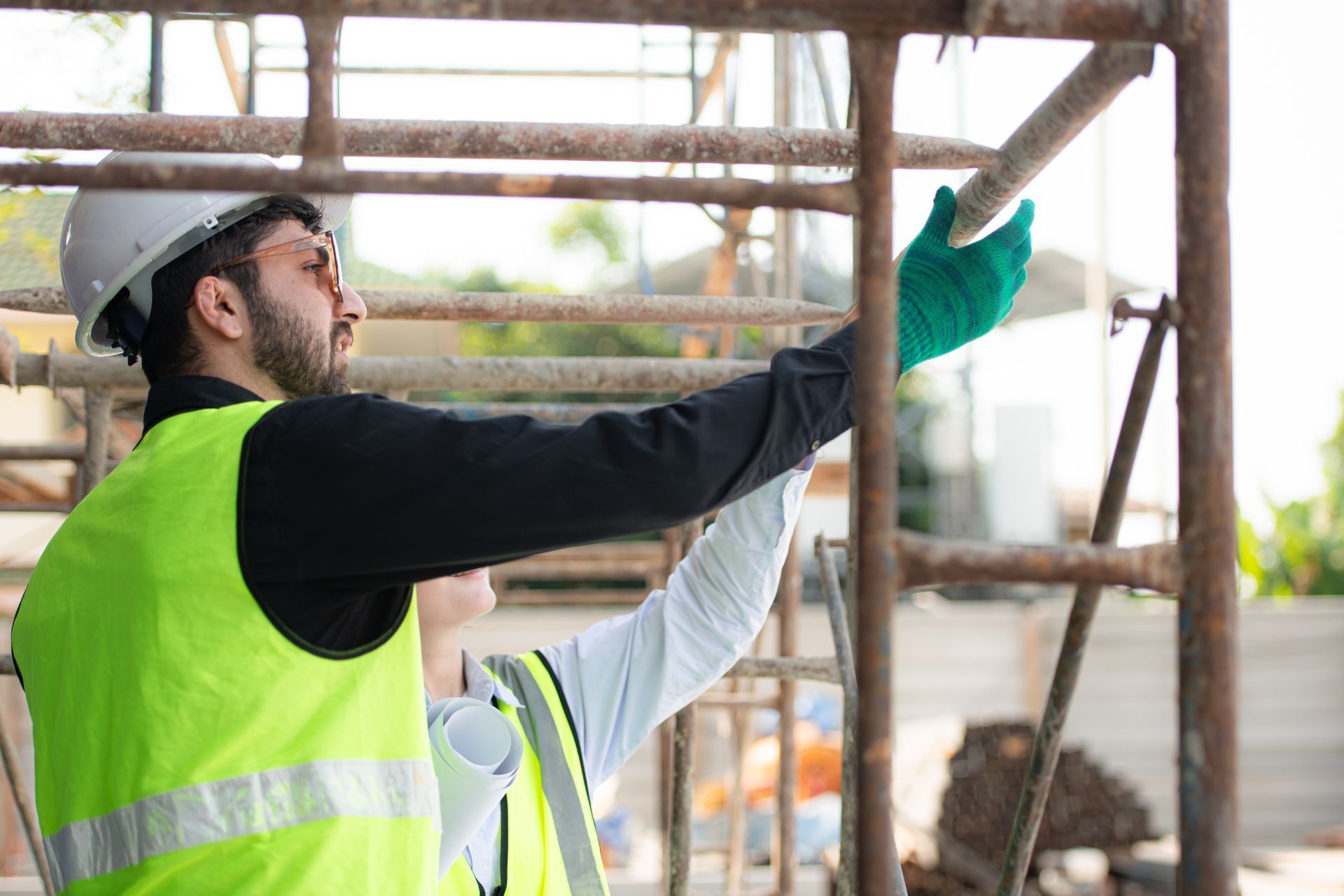 Worker in a neon vest inspecting scaffolding at a construction site
