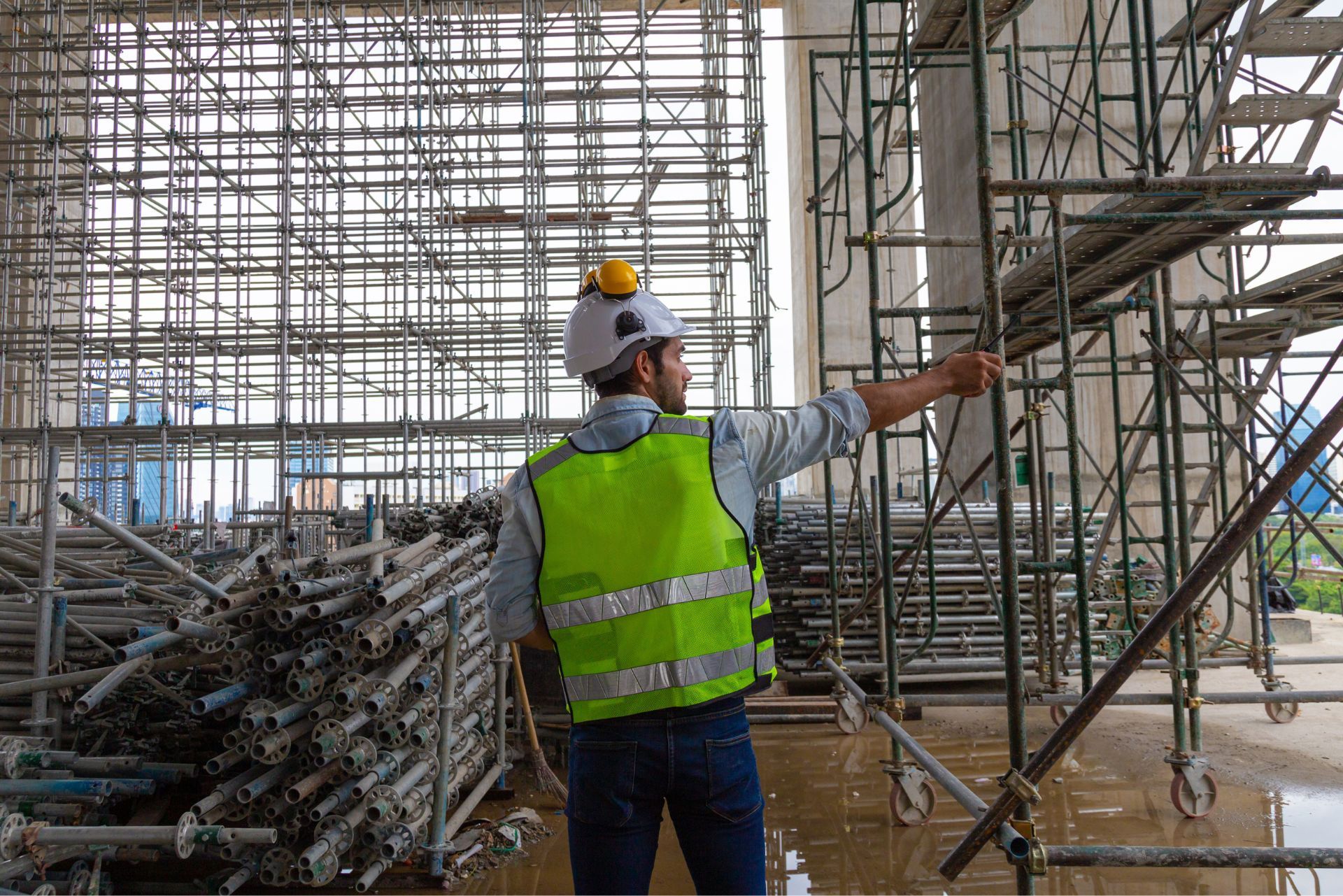 Construction worker in neon vest pointing inside a scaffolded building site