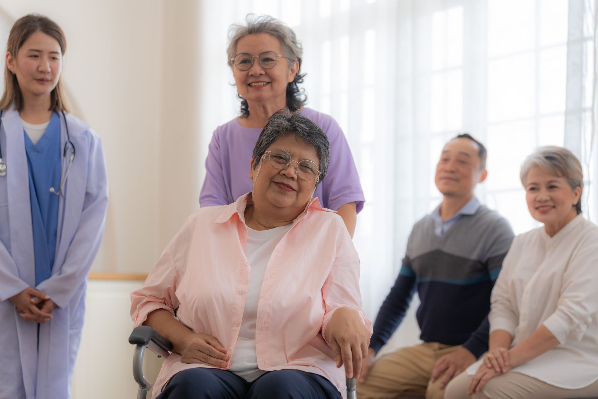 Group seated with a nurse standing beside them in a bright clinic waiting room
