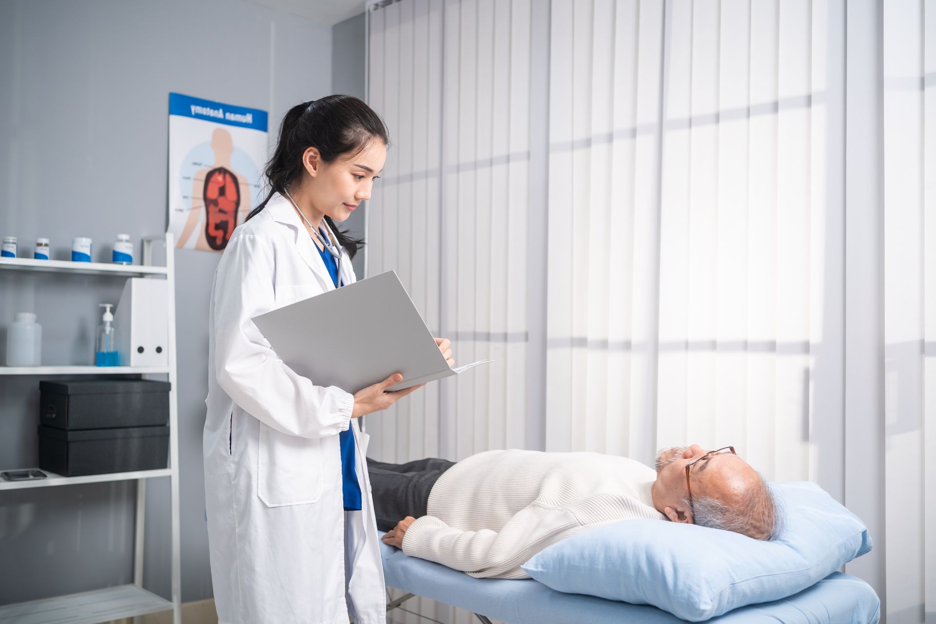 Doctor with clipboard beside a patient resting in a hospital bed