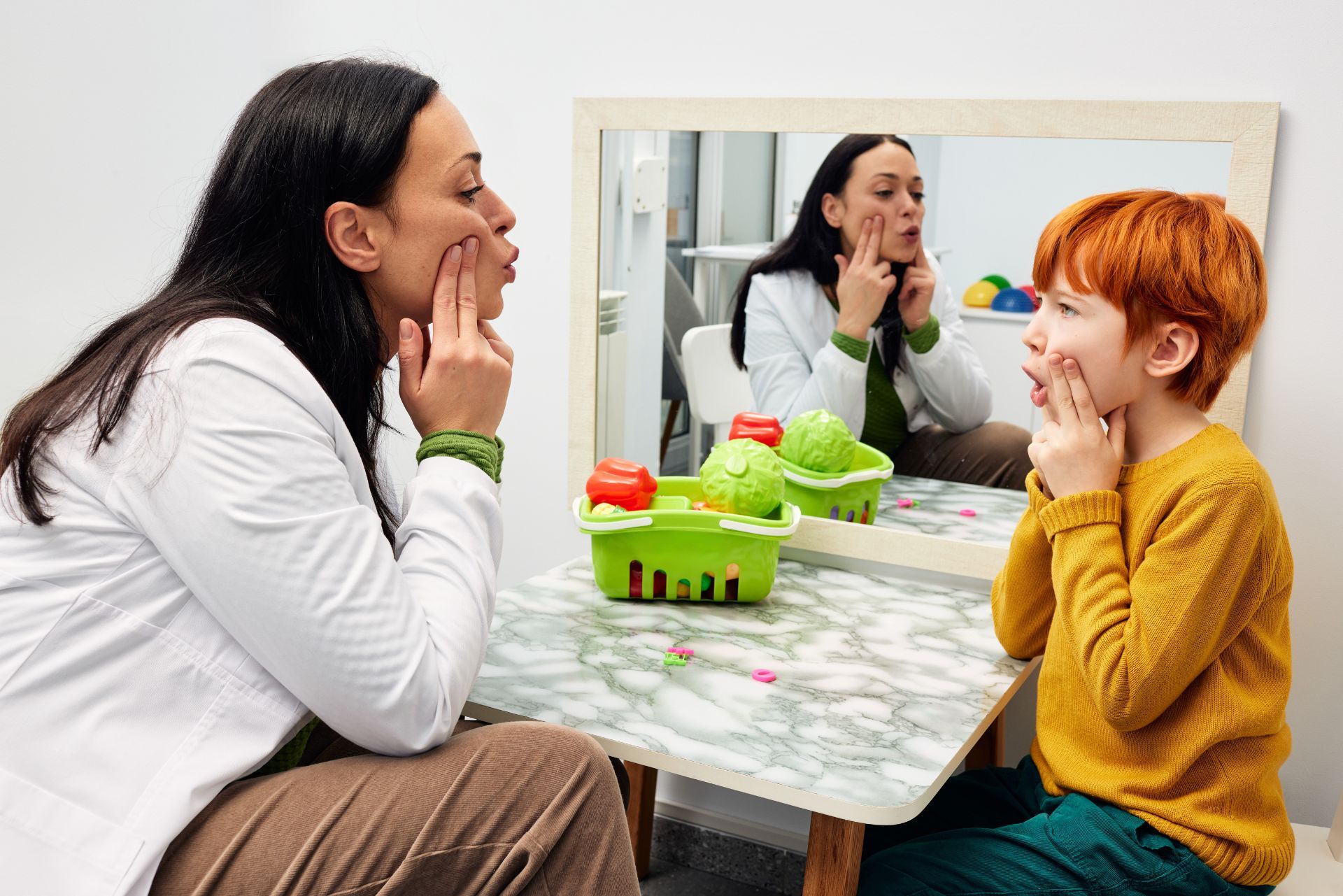 Two people smiling across a table, sharing vegetables in front of a mirror in a bright room