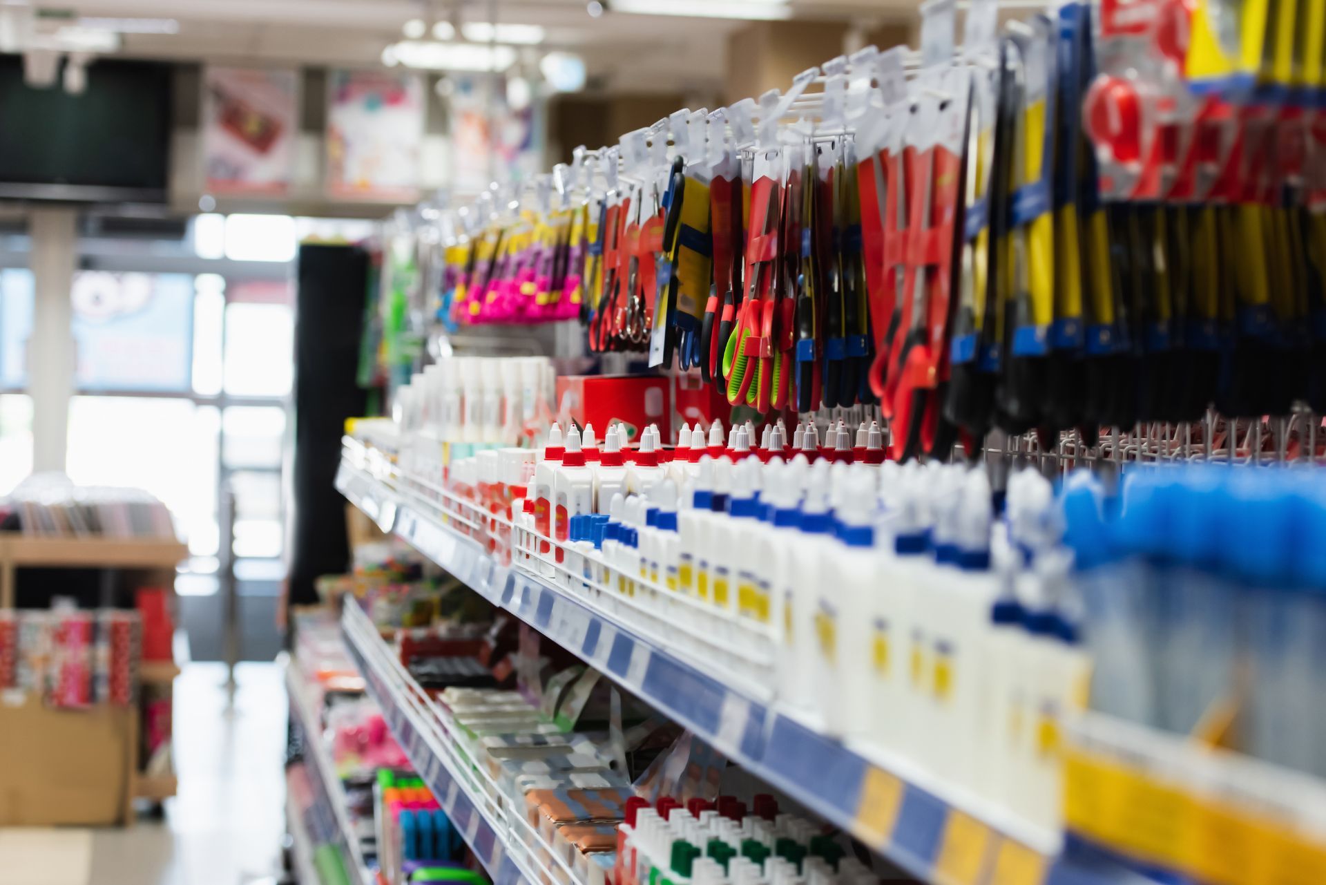A hardware store aisle with rows of hanging tools and shelves of paint supplies.