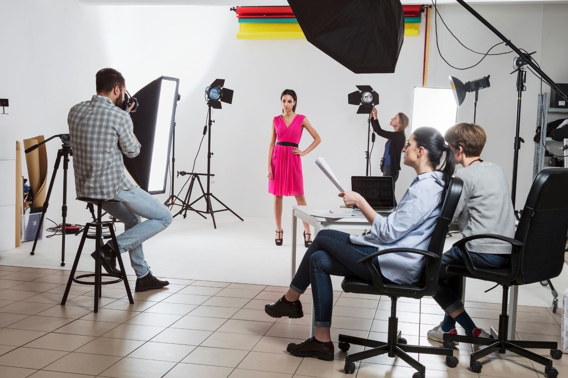 Fashion photo shoot in a studio with a model in a pink dress and crew using lights and cameras