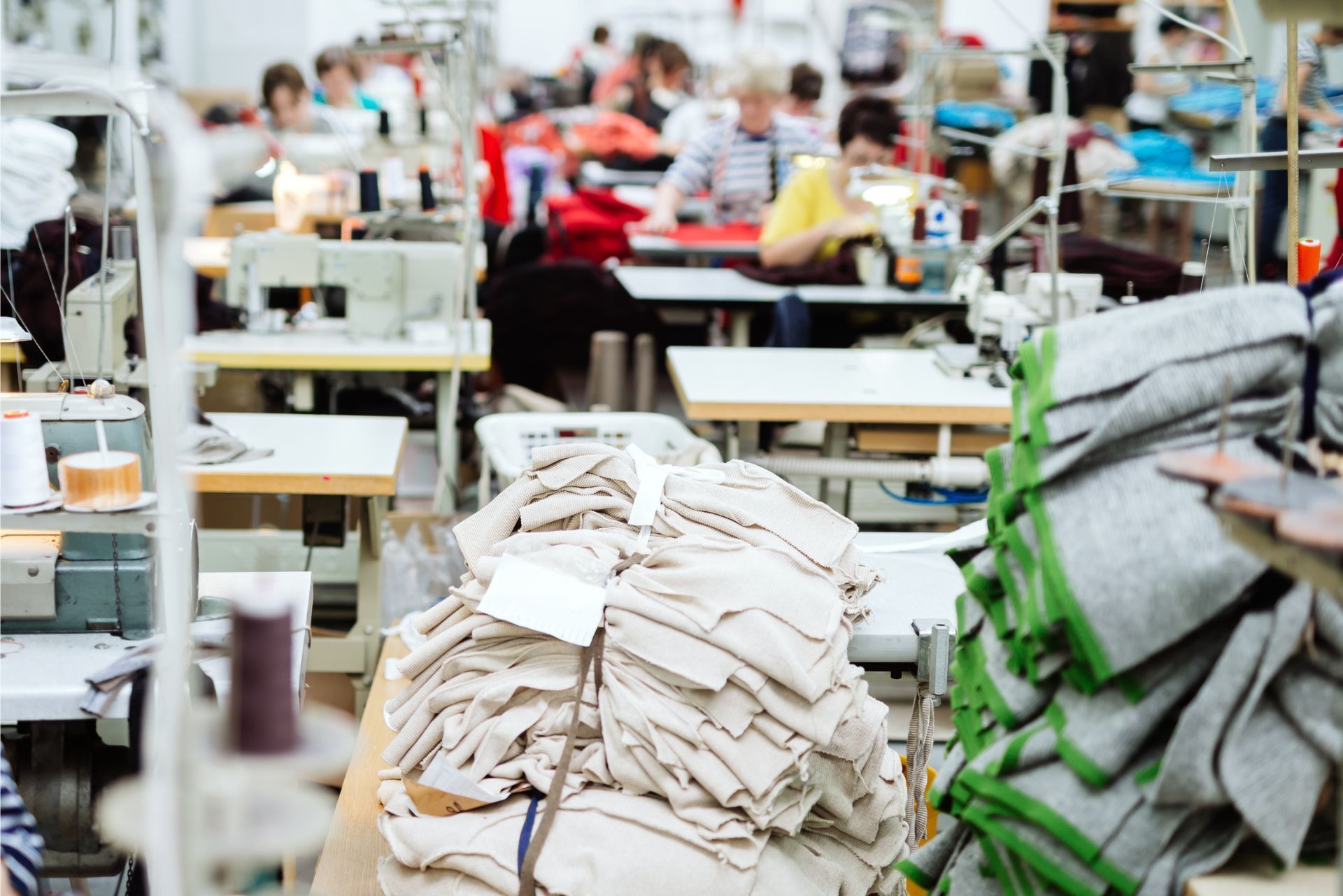 Garment factory with stacks of cut fabric and sewing machines in a busy workshop