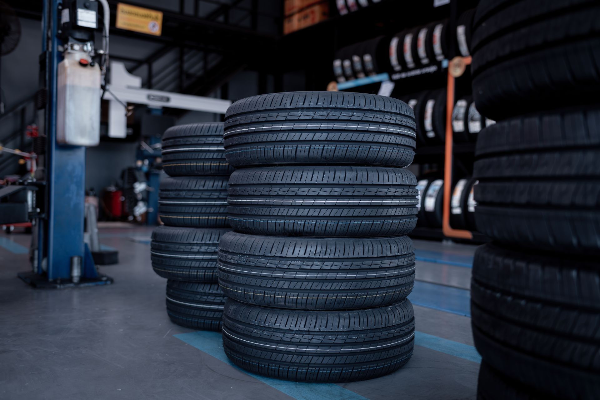 Stacked tires in an auto shop garage with a car lift in the background