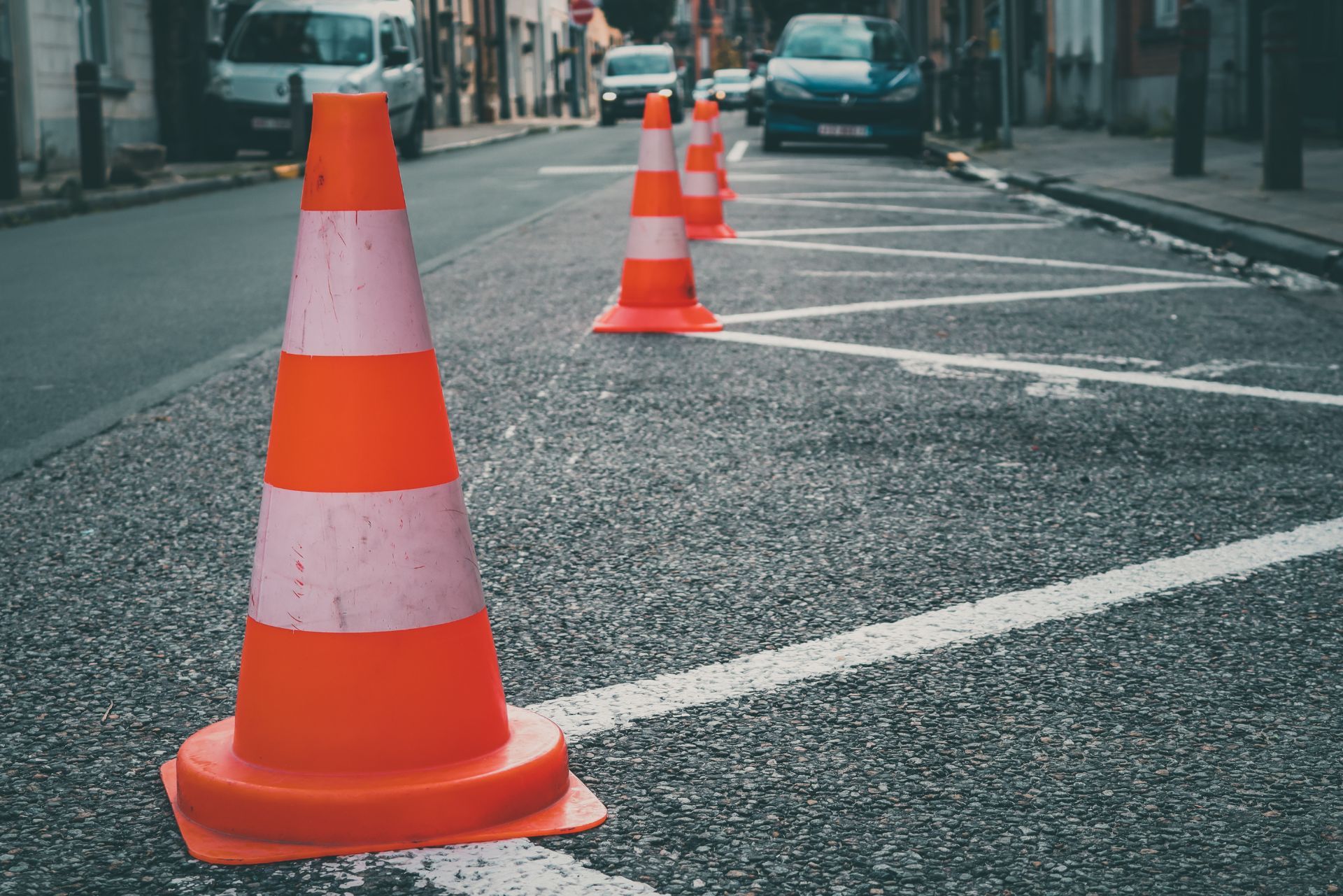 Orange and white traffic cones line a zigzagged parking prohibition marking on a city street.