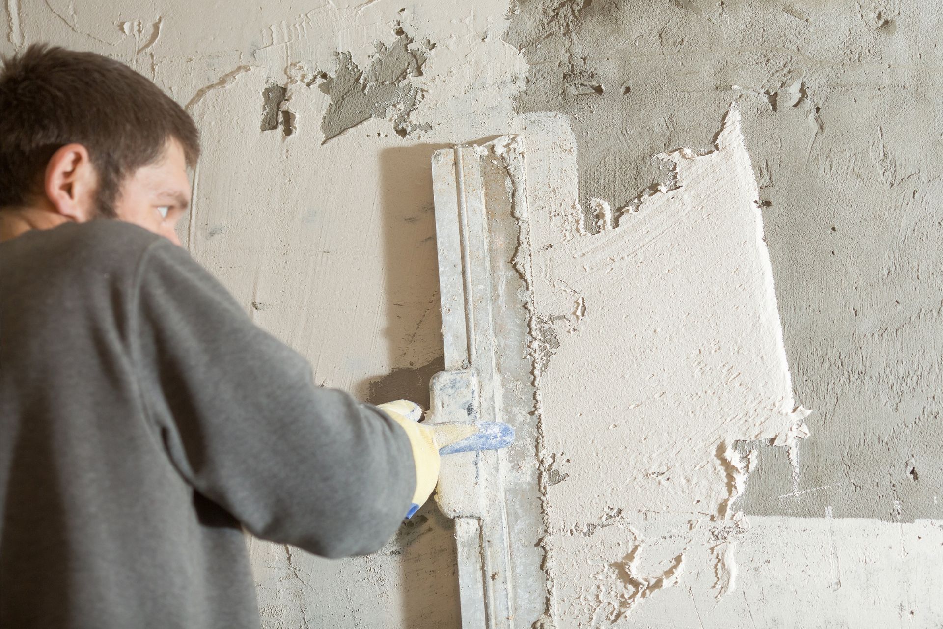 Worker applying plaster to a wall with a trowel indoors