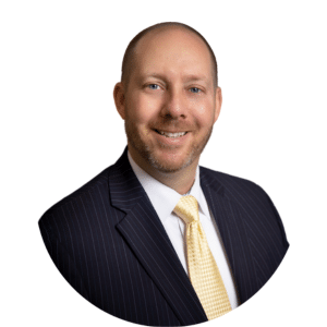 Smiling professional in a dark pinstripe suit with a yellow tie on a white background